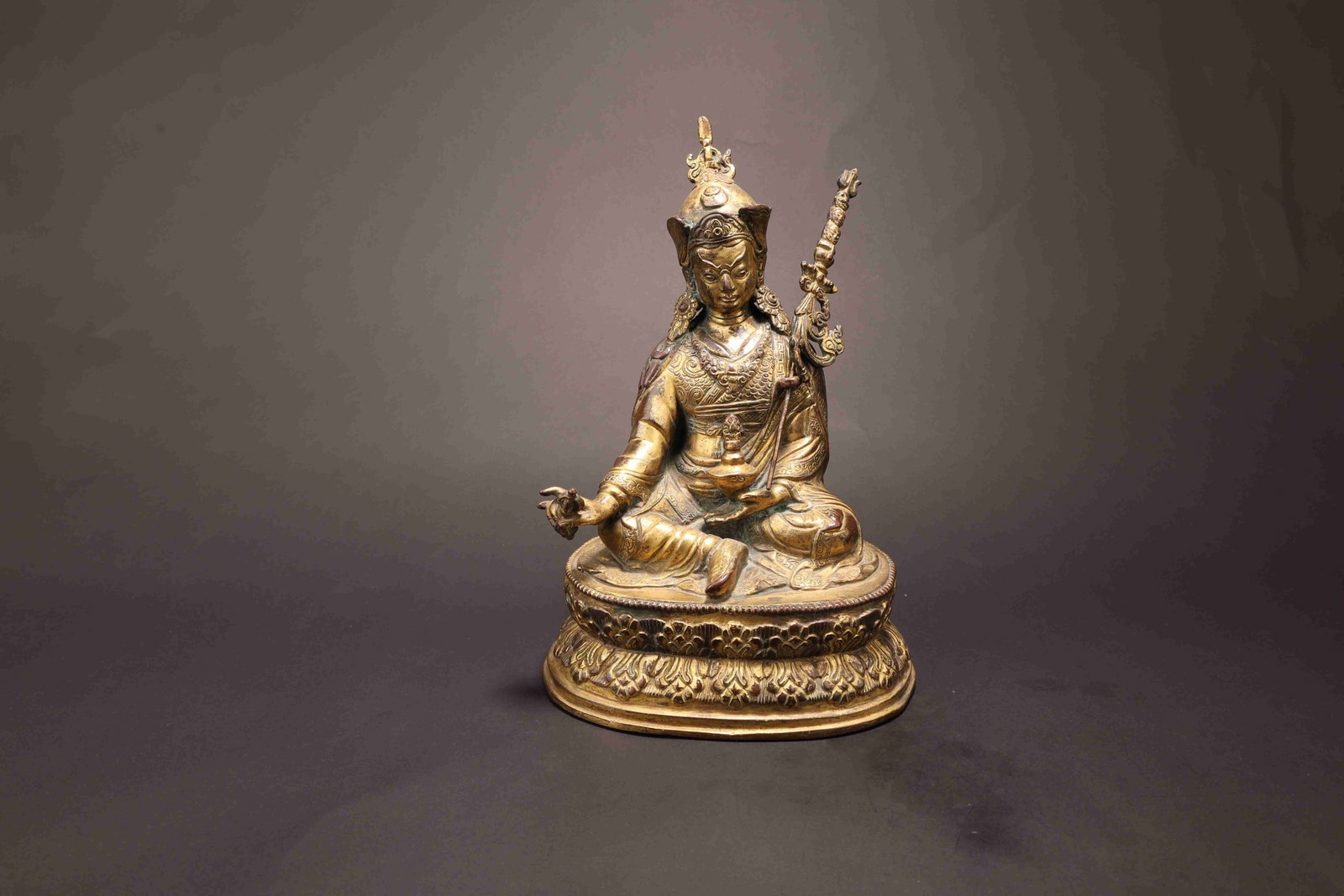 Padmasambhava (Guru Rinpoche) Gilt Bronze Figure: Padmasambhava (Guru Rinpoche) FigureSino-Tibetan, 18th-19th CenturyHeight: 23.5cm Weight: 2134gDescription: Cast in gilt bronze with a rich, honeyed patina to the exposed skin and drapery, this figure