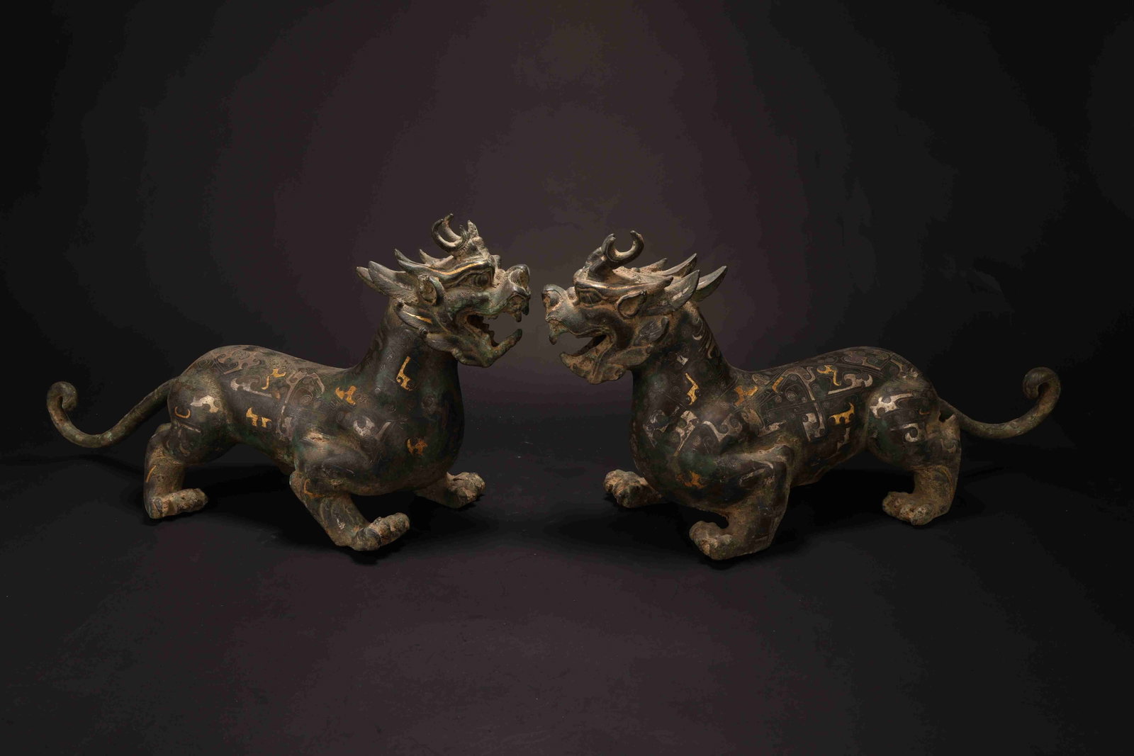 Han Dynasty Gold-and-Silver-Inlaid Mythical Qilin Ornaments, Pair: Han Dynasty Gold-and-Silver-Inlaid Qilin, Pair. Han Dynasty, 206 BC - 220 AD. Height: 47cm Width: 16cm Weight: 3300g. Description: A pair of bronze qilin cast in vigorous crouching stride, each beast 