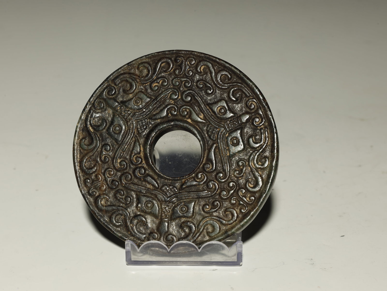 Warring States Beast-mask & Chilong Pattern Jade: AN EXCEPTIONAL WARRING STATES BEAST?MASK AND COILED CHILONG PATTERN JADE BI DISCChinese, circa 475–221 BCEHeight 8 cm × Diameter 8.5 cmDescription: Finely carved in low relief, this bi disc display