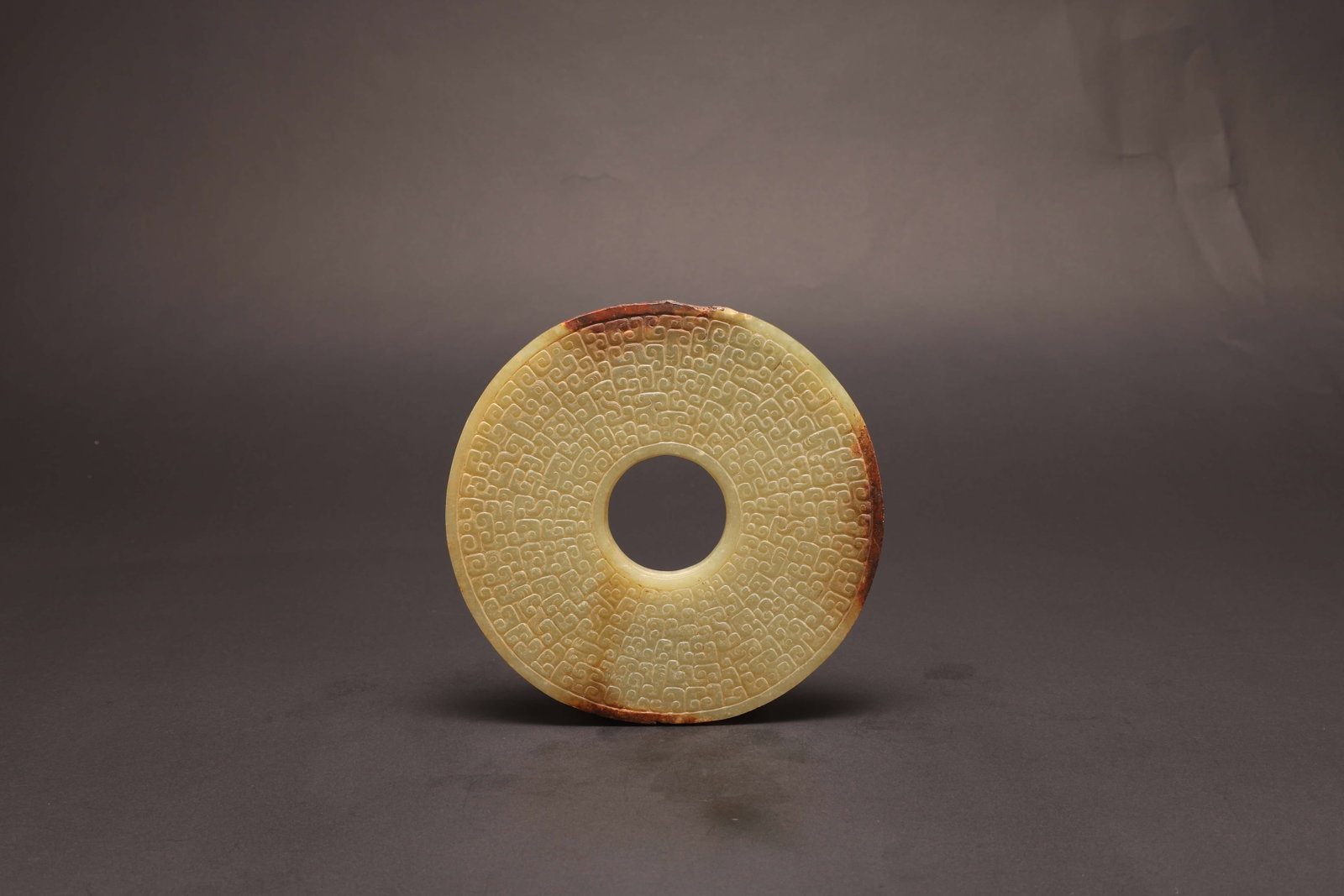 Han Dynasty Hook-Cloud Motif Jade Disc: Han Dynasty Hook-Cloud Motif Jade DiscHan DynastyDiameter: 14cm Depth: 0.4cmDescription: A flat circular jade disc carved overall with a dense repeating hook-cloud (???) motif in low relief, the patte