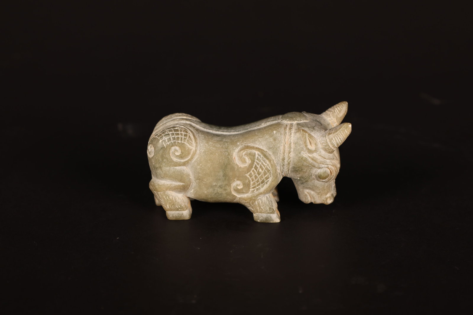 Shang Dynasty Jade Ox Hand-Held Ornament: Shang Dynasty Jade Ox Hand-Held OrnamentShang DynastyLength: 8.3cm Width: 3cm Height: 4.5cmDescription: A small jade carving of a recumbent ox, the head lowered and turned slightly to one side, short 