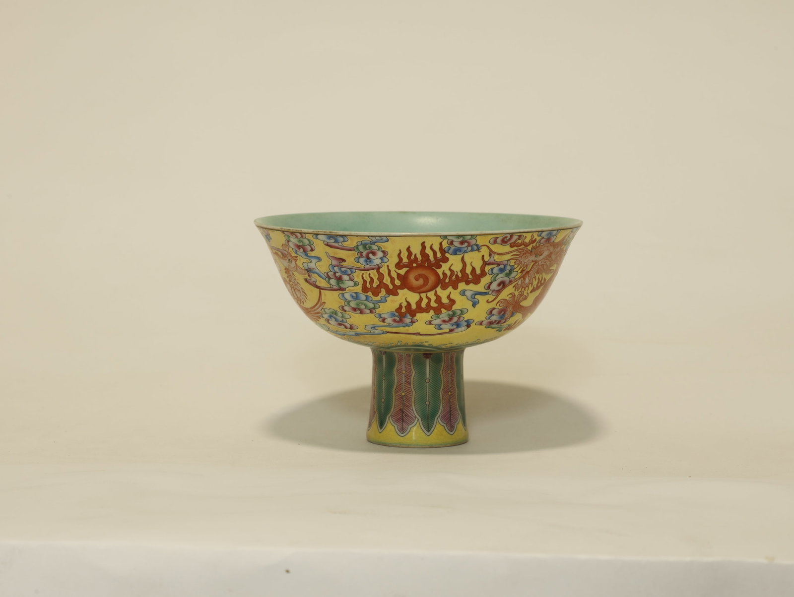 Qing Dynasty Famille Rose High-Foot Bowl with: Yellow-Ground Famille Rose High-Foot Bowl with Cloud and Dragon PatternChinese, Qing DynastyHeight 10 cm x Mouth Diameter 15 cmDescription: A famille rose stem bowl (gaozu wan) raised on a tall spread