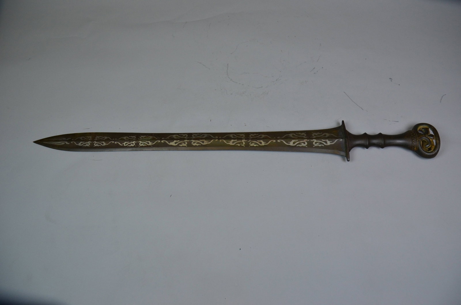 Warring States Bronze Silver-Inlaid Sword: Warring States Bronze Silver-Inlaid SwordWarring States PeriodBlade Length: 63.5cm Guard: Width: 7cm Blade Edge Width: 5cmDescription: A cast bronze sword with a straight, tapering ridged blade decora