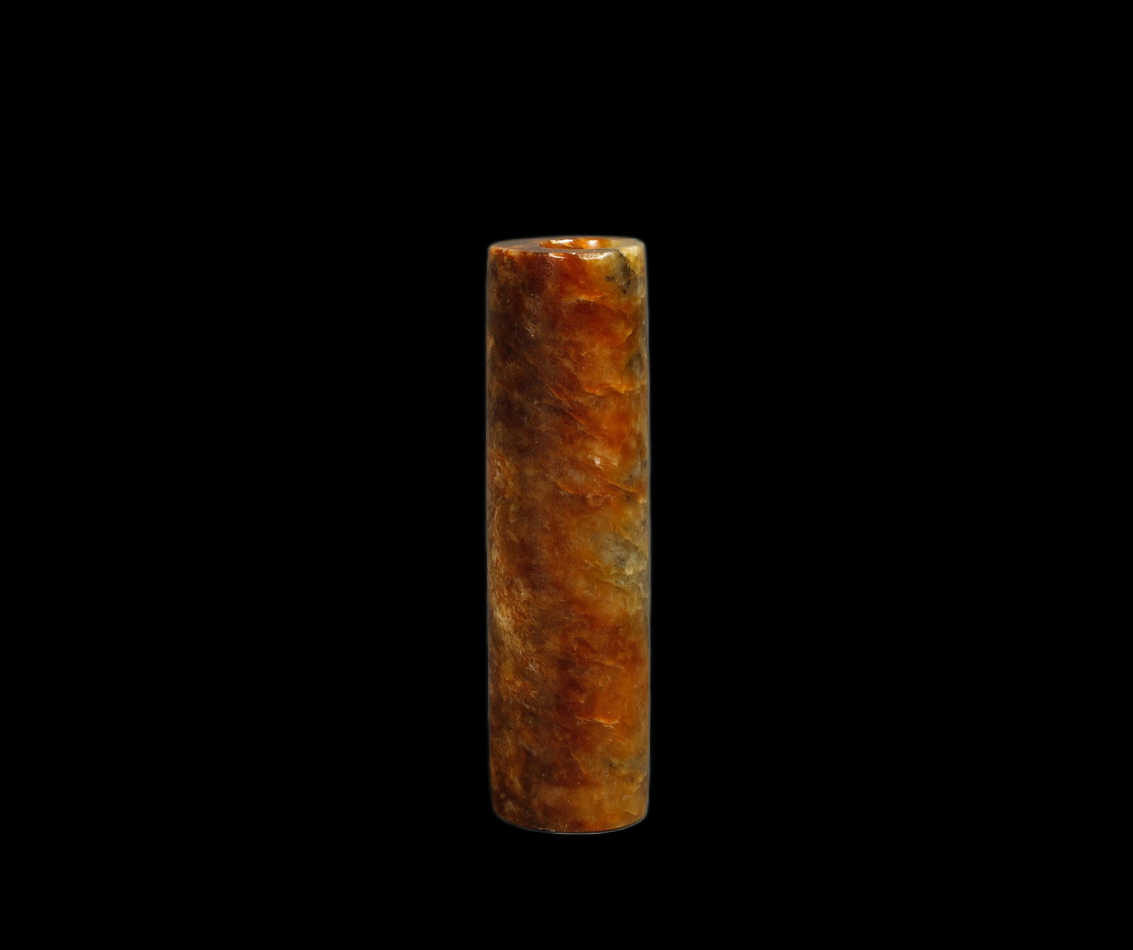 Han Dynasty Red Jade Cylinder Bead: Red Jade Cylinder BeadHan Dynasty, ChinaLength: 2 in. (5 cm); bead diameter 0.5 in. (1.3 cm)Description: A cylindrical red-toned jade bead, drilled through its length, the banded honey and russet tone