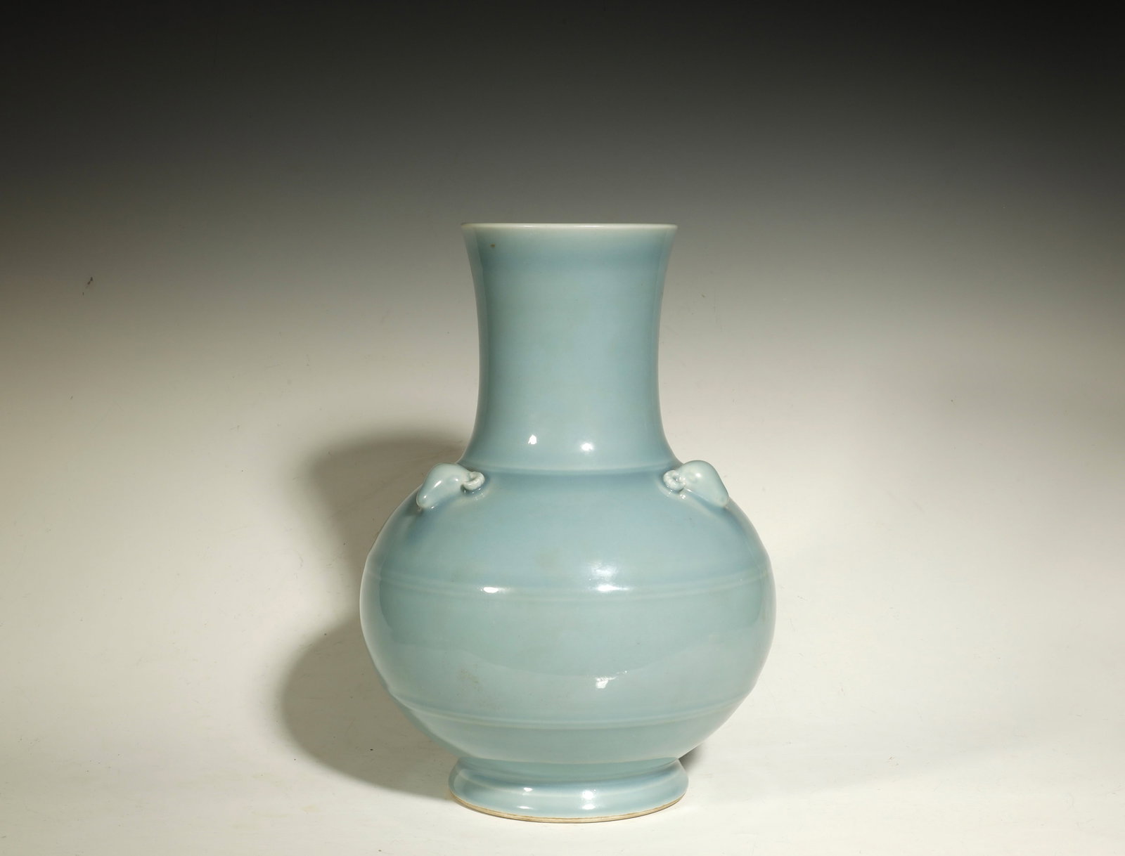 Qing Dynasty Sky-Blue Glazed Vase with Triple: A SKY-BLUE (TIANLAN) GLAZED PORCELAIN VASE WITH TRIPLE GOAT-HEAD HANDLESChina, Qing DynastyHeight: 13.4 in. (34 cm)Description: A porcelain vase with a tall trumpet neck rising from a globular body on