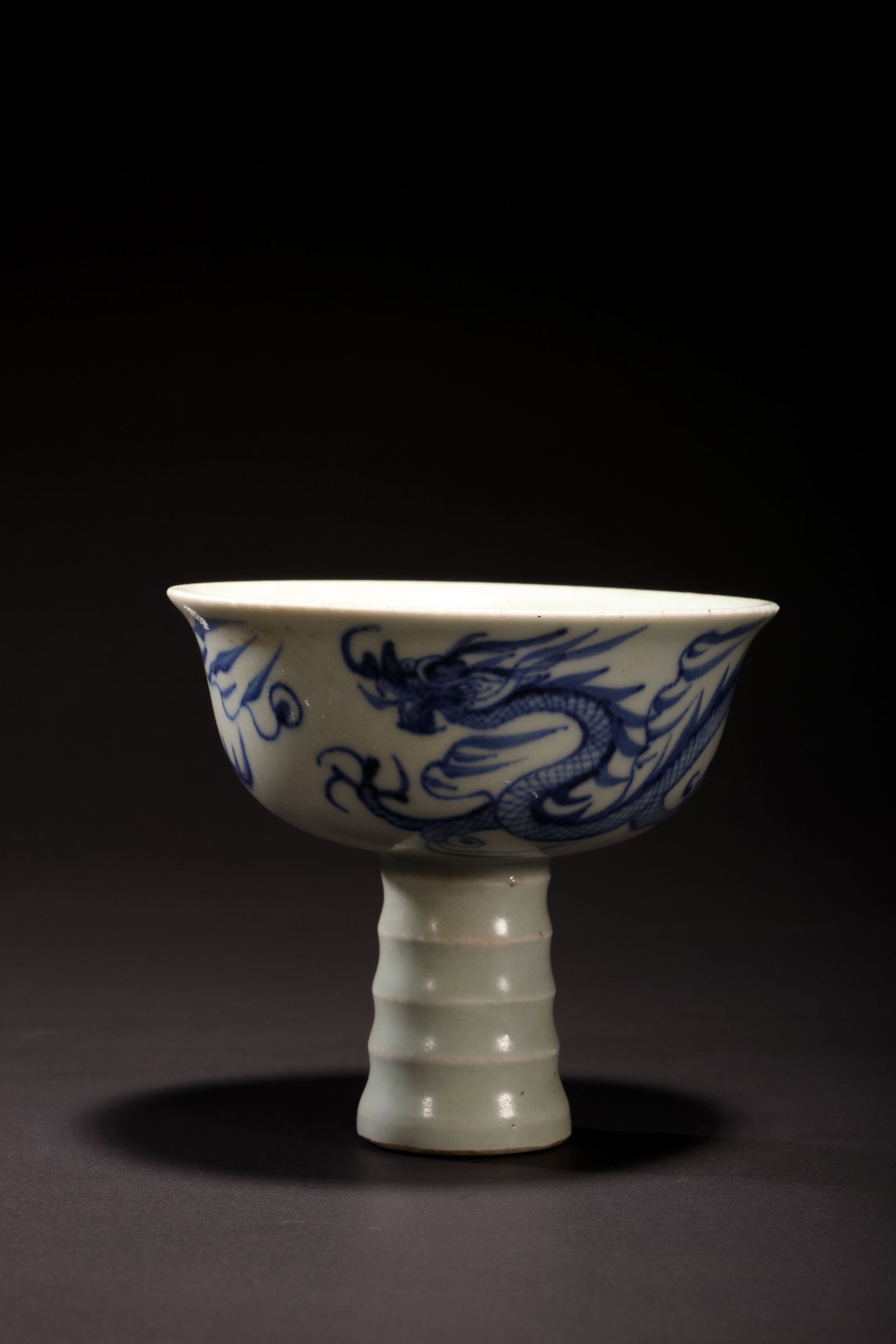 Yuan Dynasty Blue-and-White Dragon-Motif Stem Cup: Yuan Dynasty Blue-and-White Dragon-Motif Stem CupYuan DynastyHeight: 8.5cm Mouth Diameter: 8.5cmDescription: A porcelain stem cup, the flared bowl painted in underglaze blue with a striding scaly drag