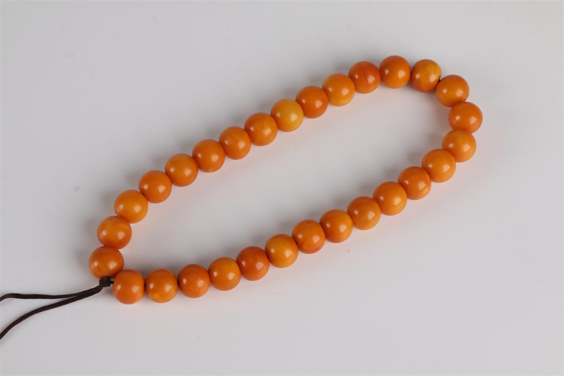 A STRING OF HANDHELD AMBER BEESWAX BEADS. (1 of 7)