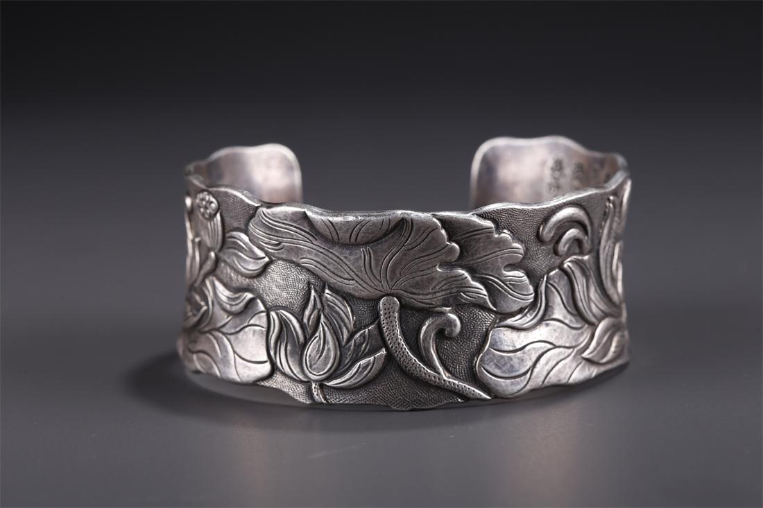 A SILVER BANGLE WITH LOTUS FLOWERS DESIGN. (1 of 8)