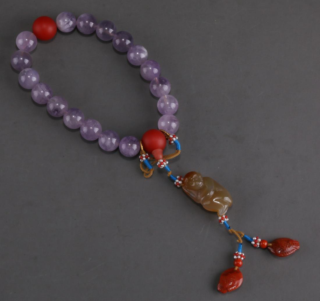 A STRING OF HANDHELD AMETHYST BEADS. (1 of 9)