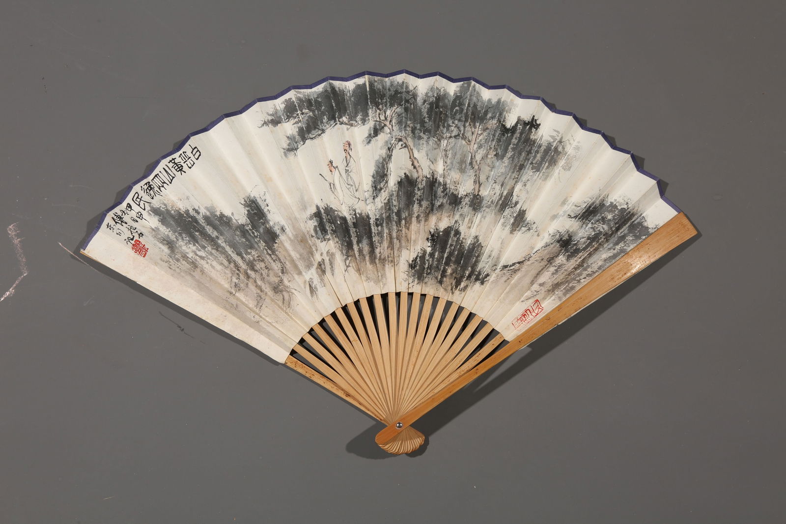 A PAPER FAN PAINTED BY FU BAOSHI WITH LANDSCAPE AND FIGURES.傅抱石: paper fan painted by Fu Baoshi with landscape and figures.傅抱石