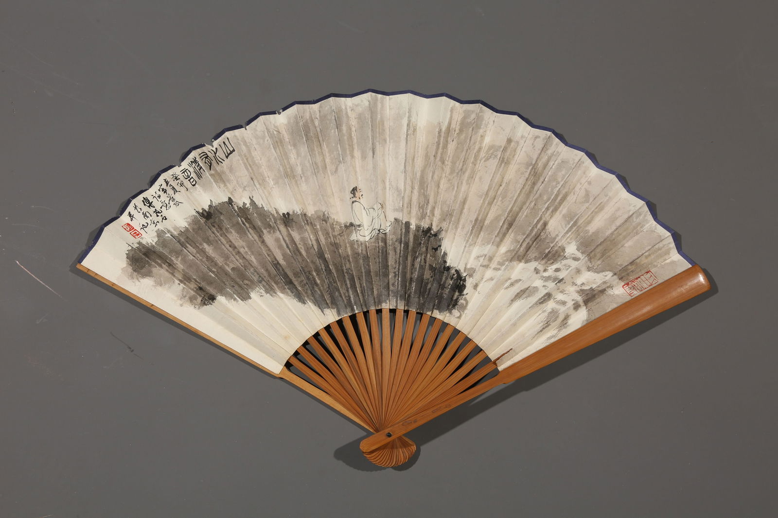 A PAPER FAN PAINTED BY FU BAOSHI WITH LANDSCAPE AND FIGURES.傅抱石: paper fan painted by Fu Baoshi with landscape and figures.傅抱石