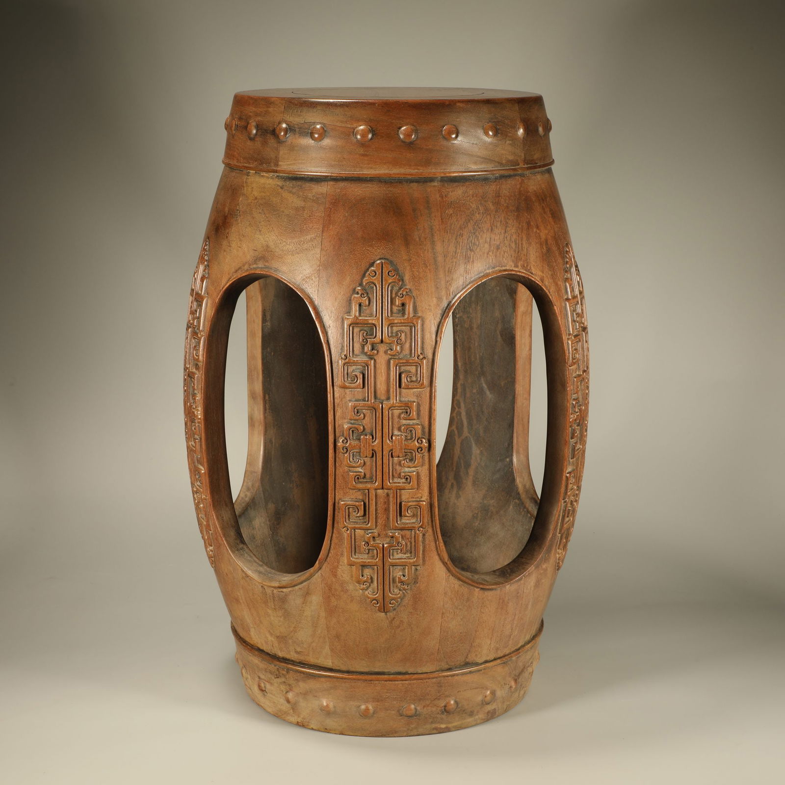 A HUANGHUALI WOOD DRUM-SHAPED STOOL WITH COILING DRAGON MOTIF: Huanghuali wood drum-shaped stool with coiling dragon motif