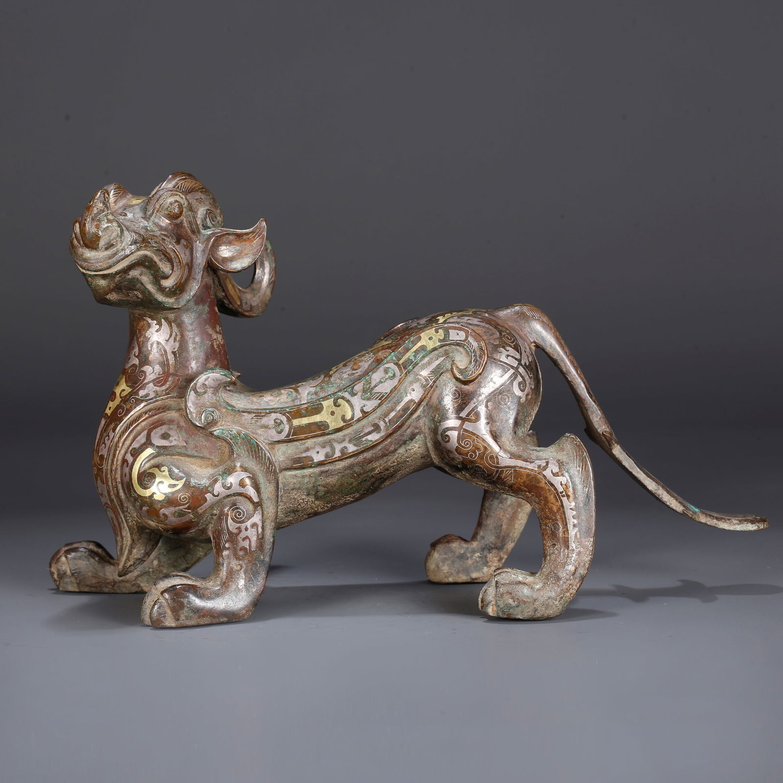 A BRONZE INLAID WITH GOLD AND SILVER CHI TIGER-SHAPED FIGURINE: Bronze Inlaid with Gold and Silver Chi Tiger-Shaped Figurine