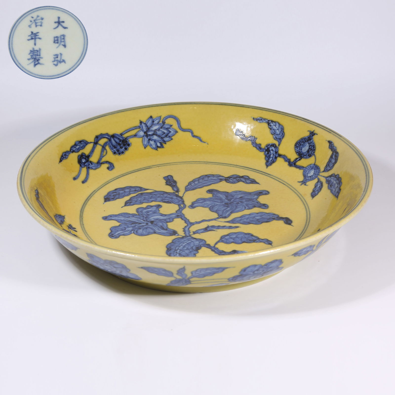 A YELLOW-GROUND BLUE-AND-WHITE PLATE WITH FLORAL AND FRUIT SPRAYS: Yellow-Ground Blue-and-White Plate with Floral and Fruit Sprays