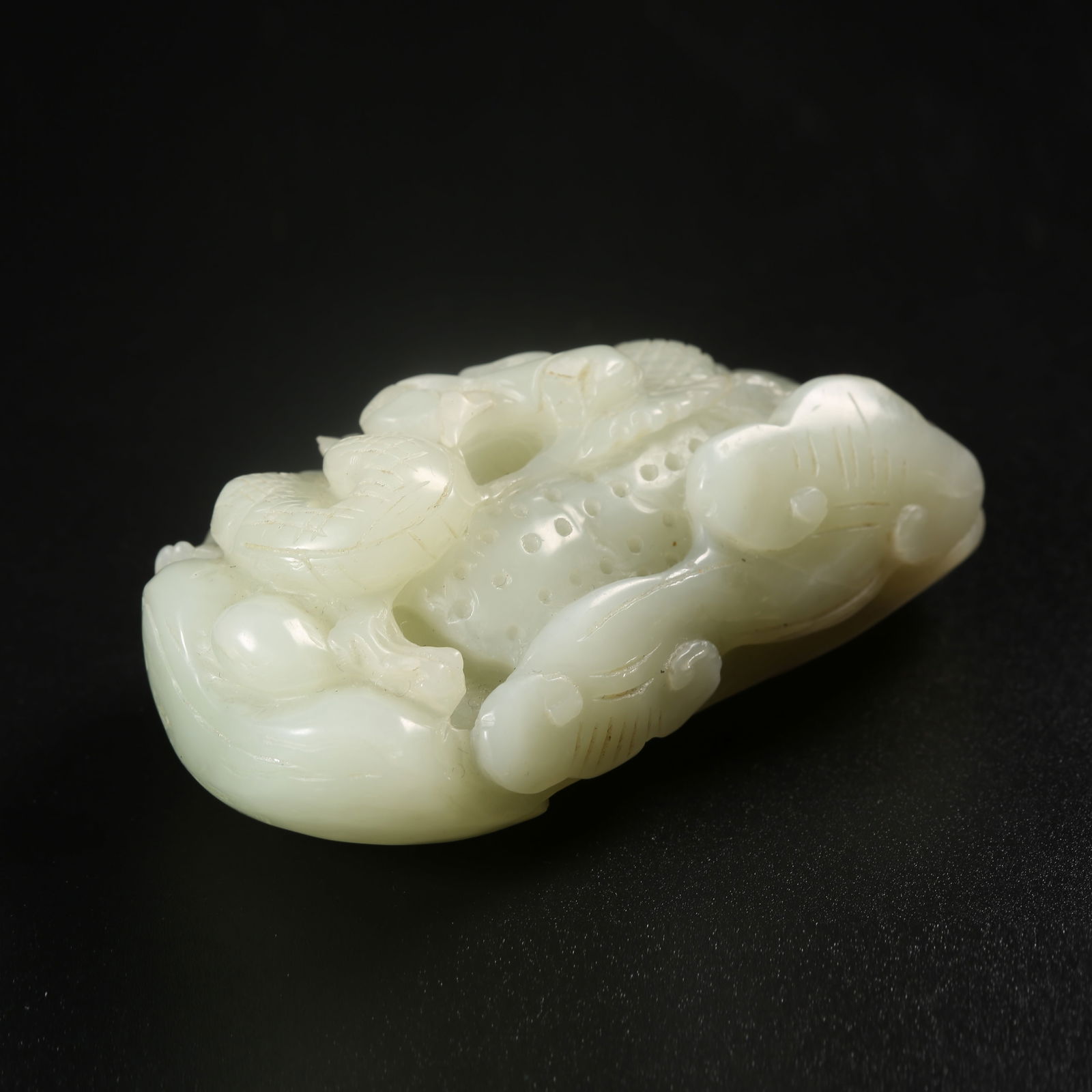 A HETIAN JADE HANDHELD CARVING WITH DRAGON MOTIFS: Hetian jade handheld carving with dragon motifs