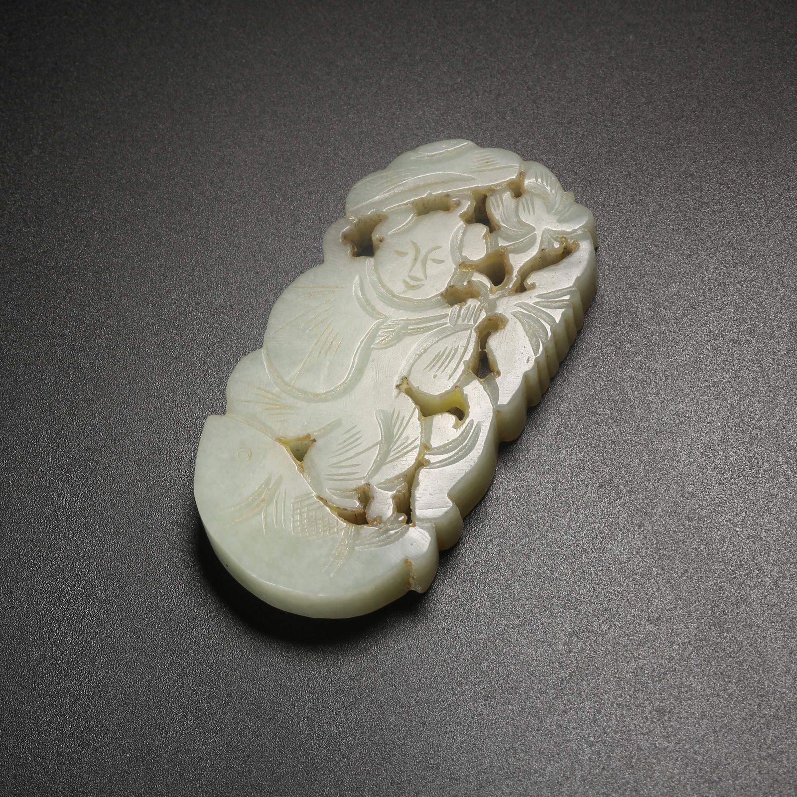 A HETIAN JADE PENDANT CARVED WITH A CHILD HOLDING A LOTUS: Hetian jade pendant carved with a child holding a lotus