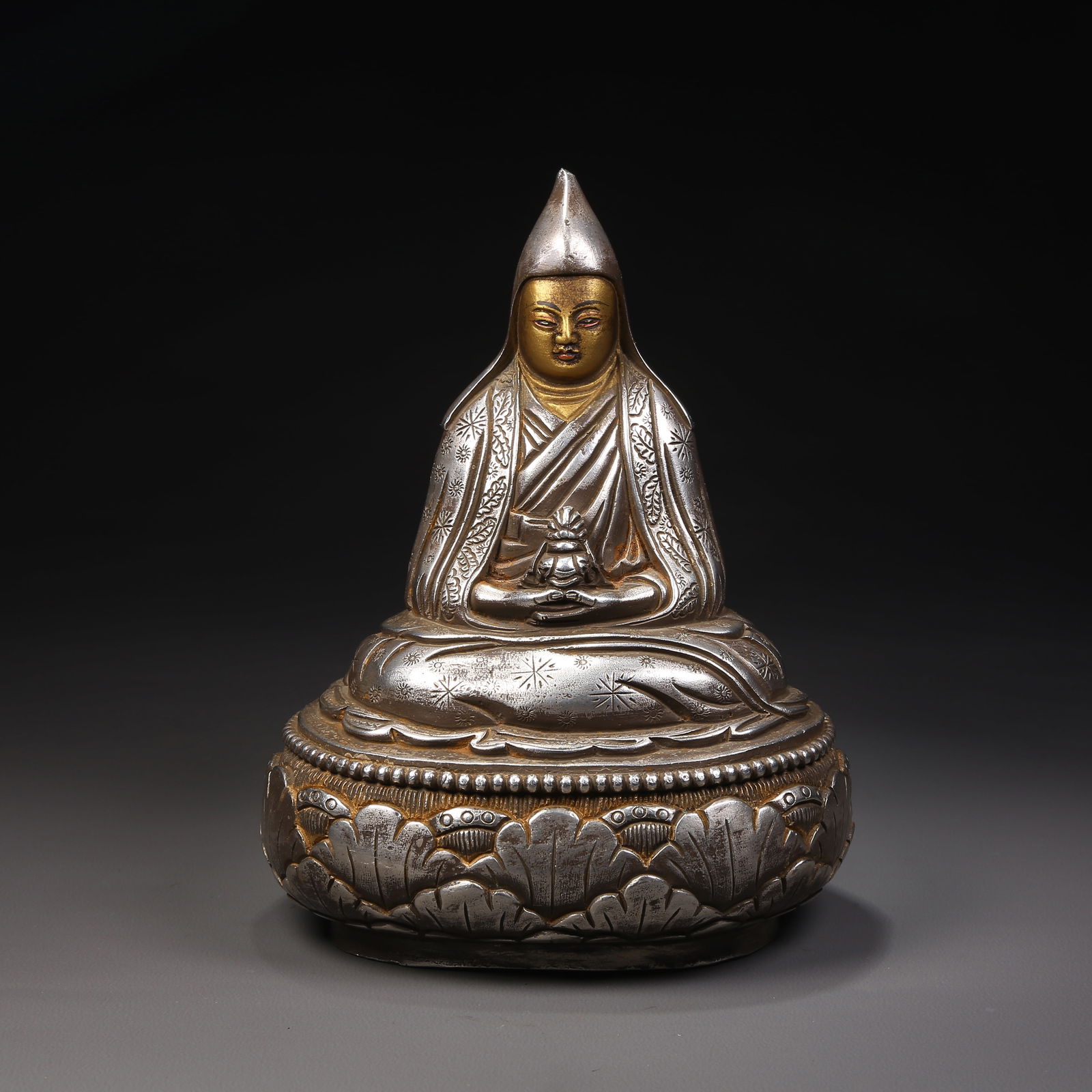 A GILDED SILVER-ON-BRONZE GURU STATUE: Gilded silver-on-bronze guru statue