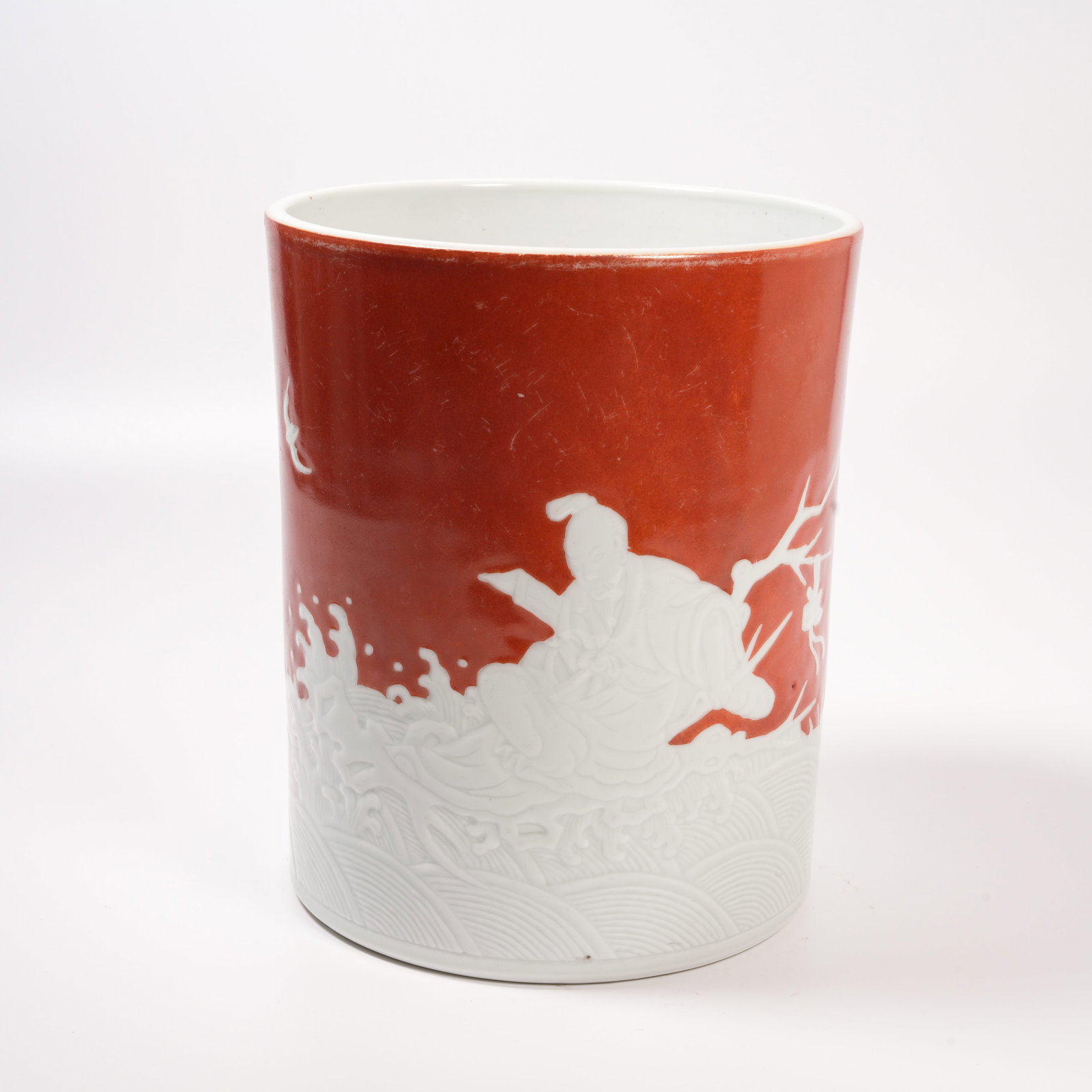 A JUJUBE-RED CARVED PORCELAIN BRUSH HOLDER WITH FIGURAL MOTIFS: Jujube-Red Carved Porcelain Brush Holder with Figural Motifs