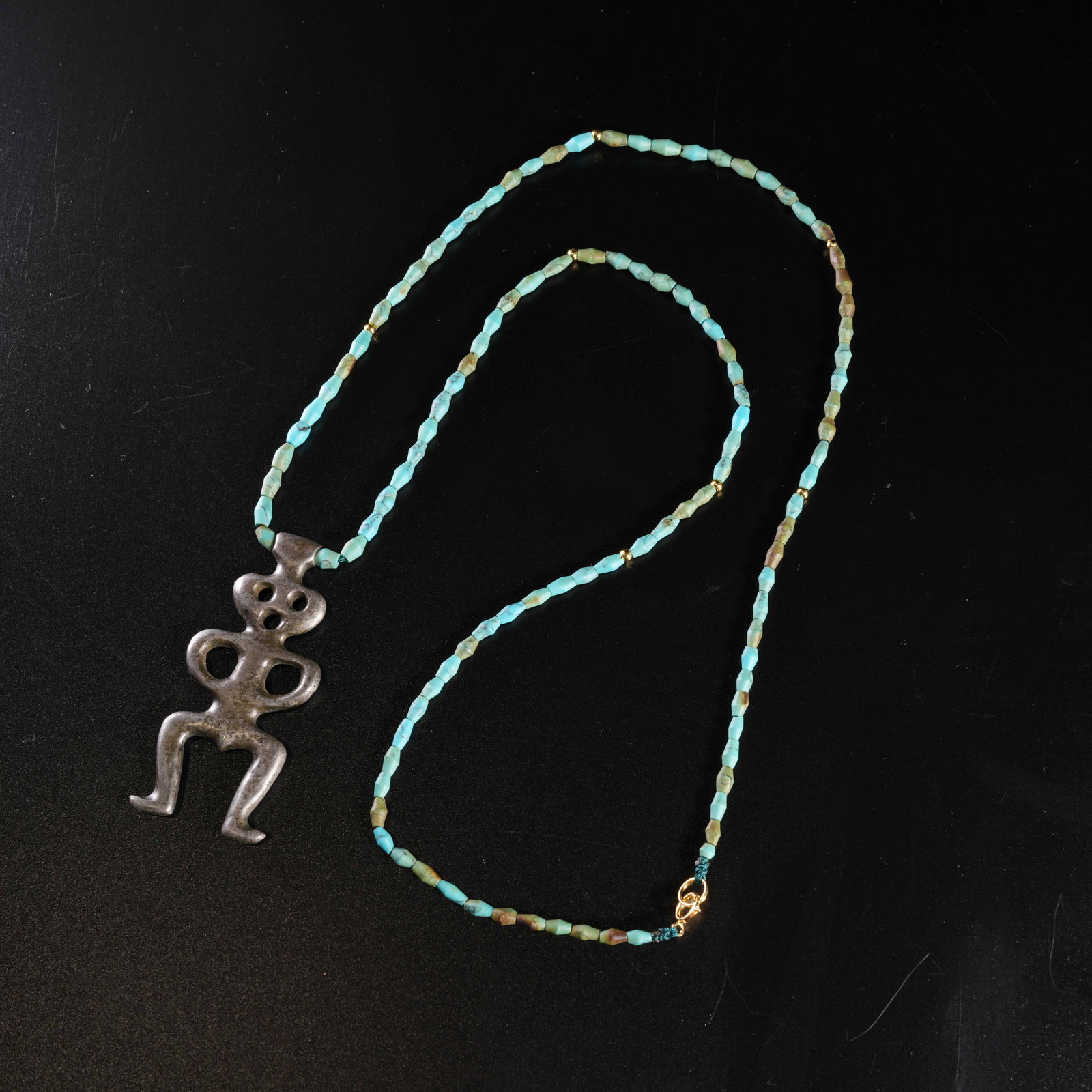A IRON ANTHROPOMORPHIC PENDANT WITH TURQUOISE NECKLACE: Iron anthropomorphic pendant with turquoise necklace
