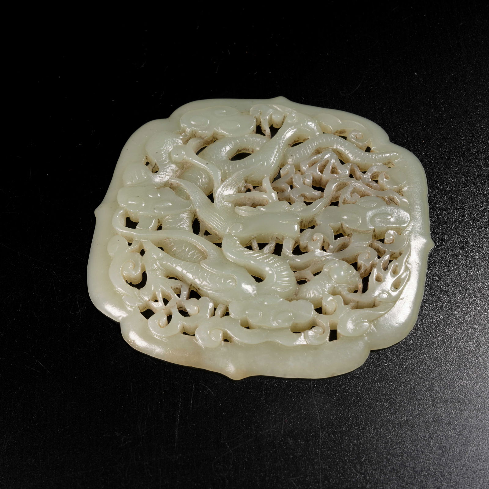 A HETIAN JADE CLOUD-AND-DRAGON MOTIF PENDANT: Hetian Jade Cloud-and-Dragon Motif Pendant