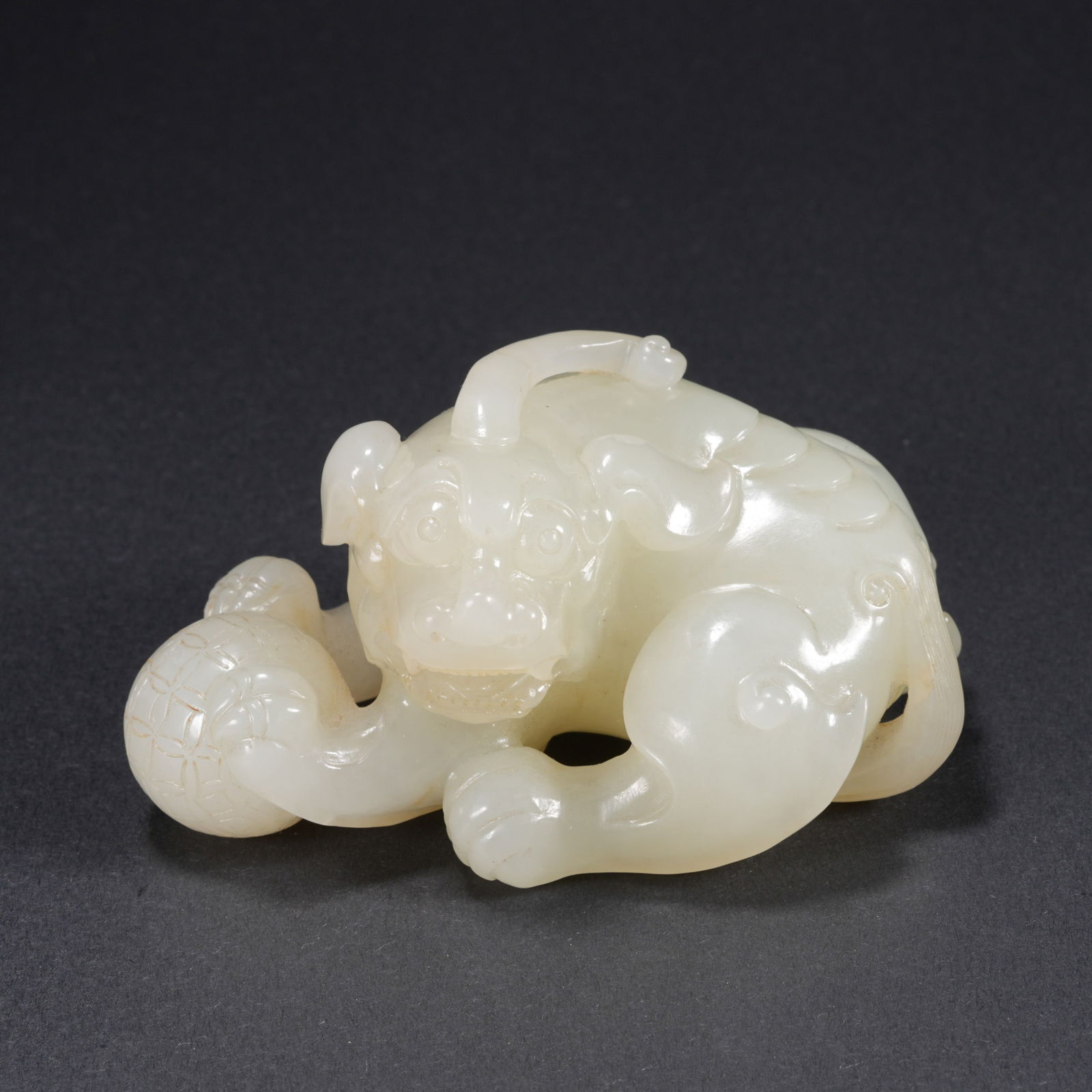 A HETIAN JADE CARVED LION PLAYING WITH BROCADE BALL FIGURE: Hetian Jade Carved Lion Playing with Brocade Ball Figure