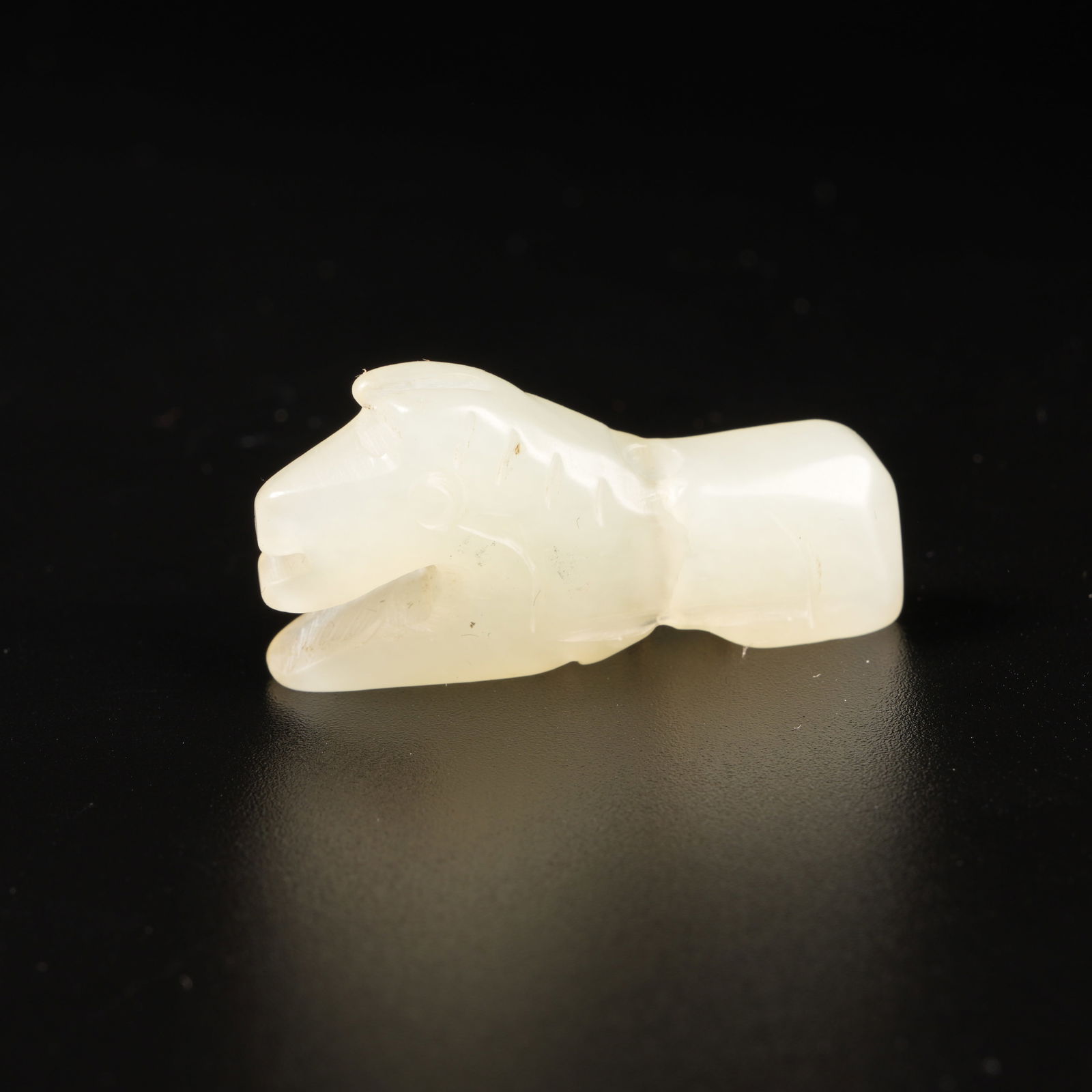 A HETIAN JADE RECLINING HORSE PENDANT: Hetian Jade Reclining Horse Pendant