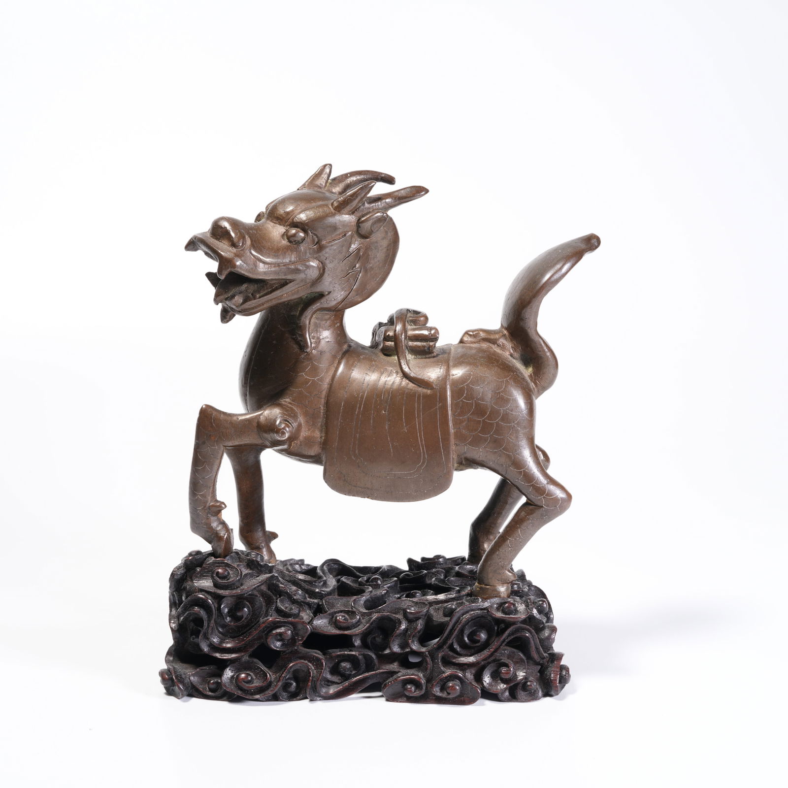 A BRONZE QILIN CARRYING A BOOK ORNAMENT: Bronze Qilin Carrying a Book Ornament