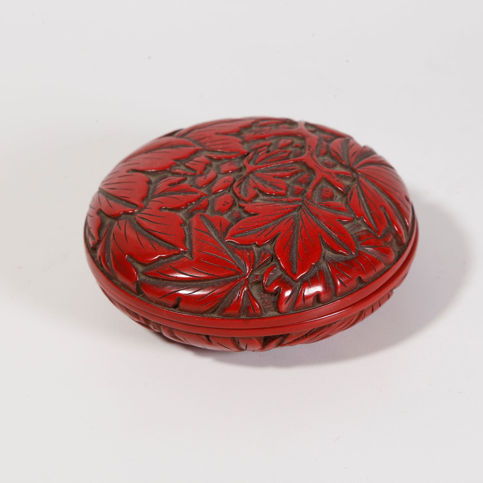 A CARVED RED LACQUER COVERED BOX WITH FLORAL MOTIF: Carved red lacquer covered box with floral motif