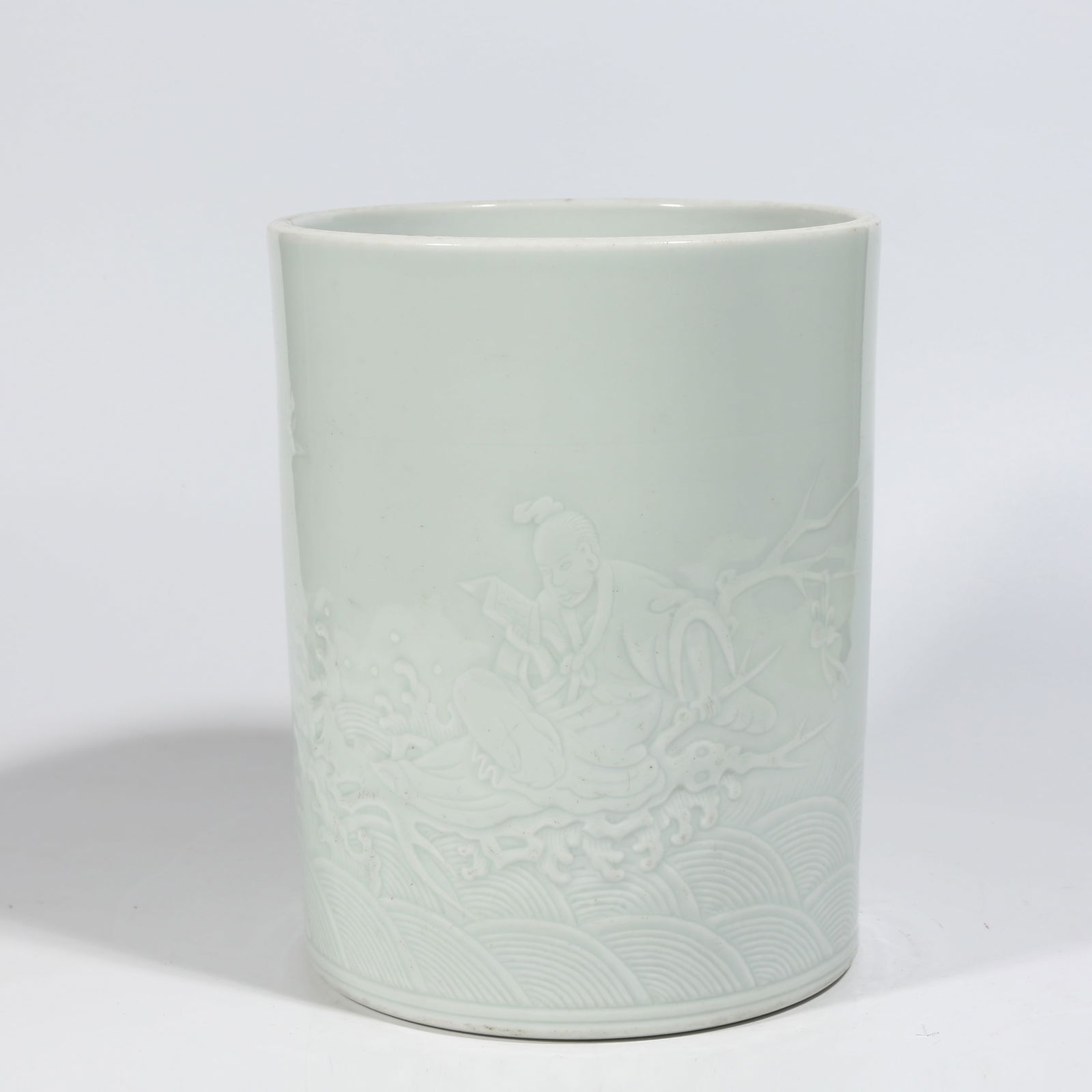 A WHITE-GLAZED BRUSH POT WITH INCISED DESIGN OF IMMORTAL RIDING A LOG RAFT: White-glazed brush pot with incised design of immortal riding a log raft