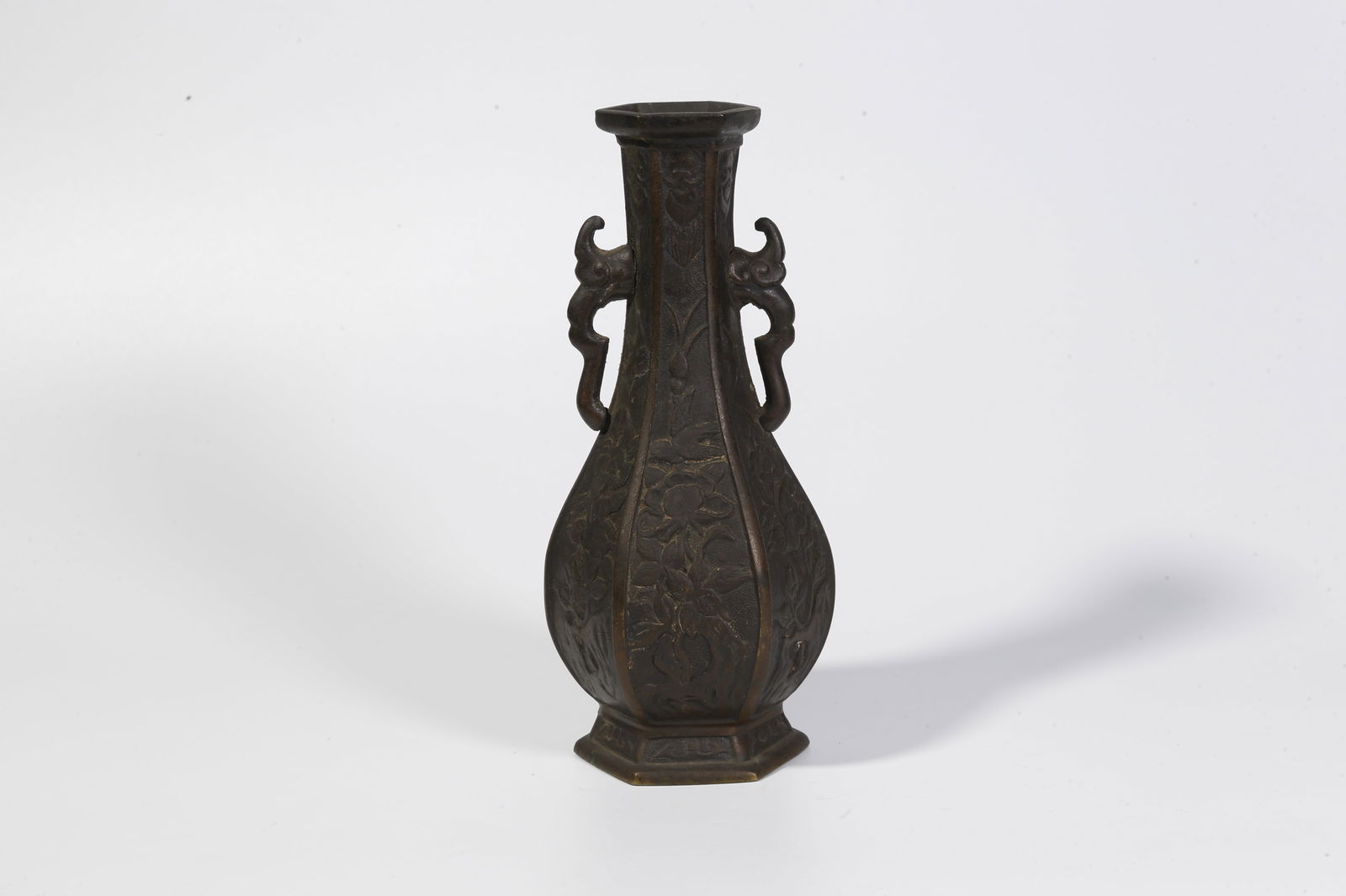A BRONZE DOUBLE-HANDLED BOTTLE WITH FLORAL MOTIF: Bronze double-handled bottle with floral motif