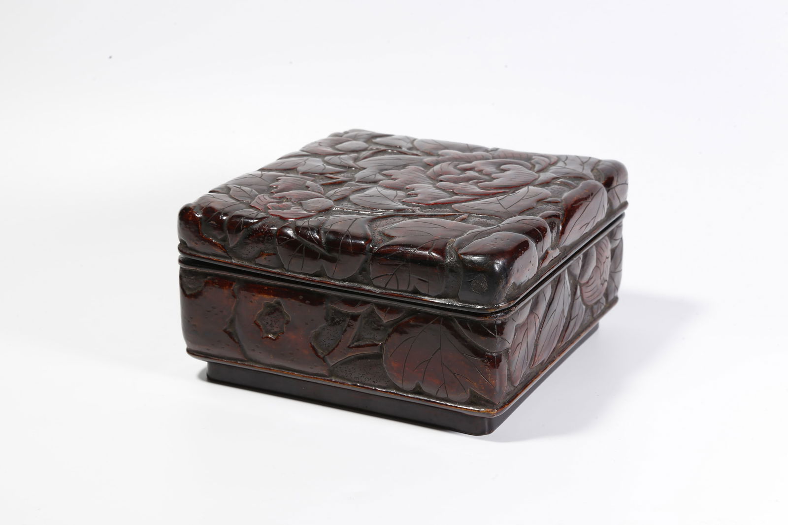 A RED LACQUER COVERED BOX WITH FLORAL MOTIF: Red lacquer covered box with floral motif