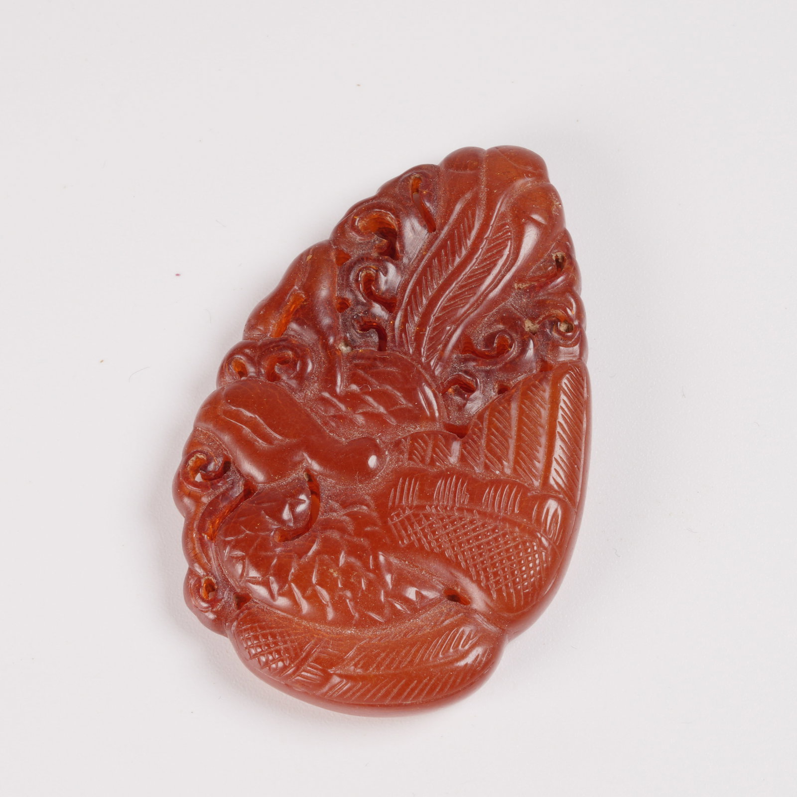 A HONEY-AMBER PENDANT WITH PHOENIX MOTIF: Honey-amber pendant with phoenix motif