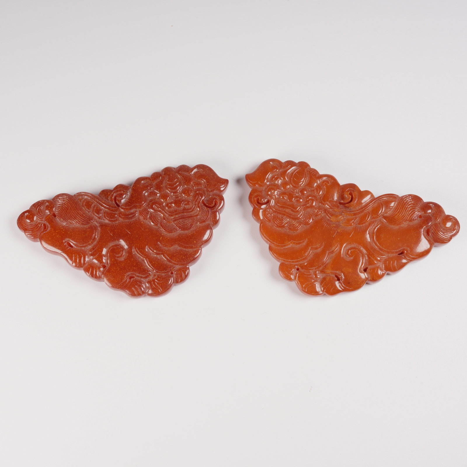 A SET OF HONEY-AMBER PENDANTS WITH AUSPICIOUS LION MOTIFS: Set of honey-amber pendants with auspicious lion motifs