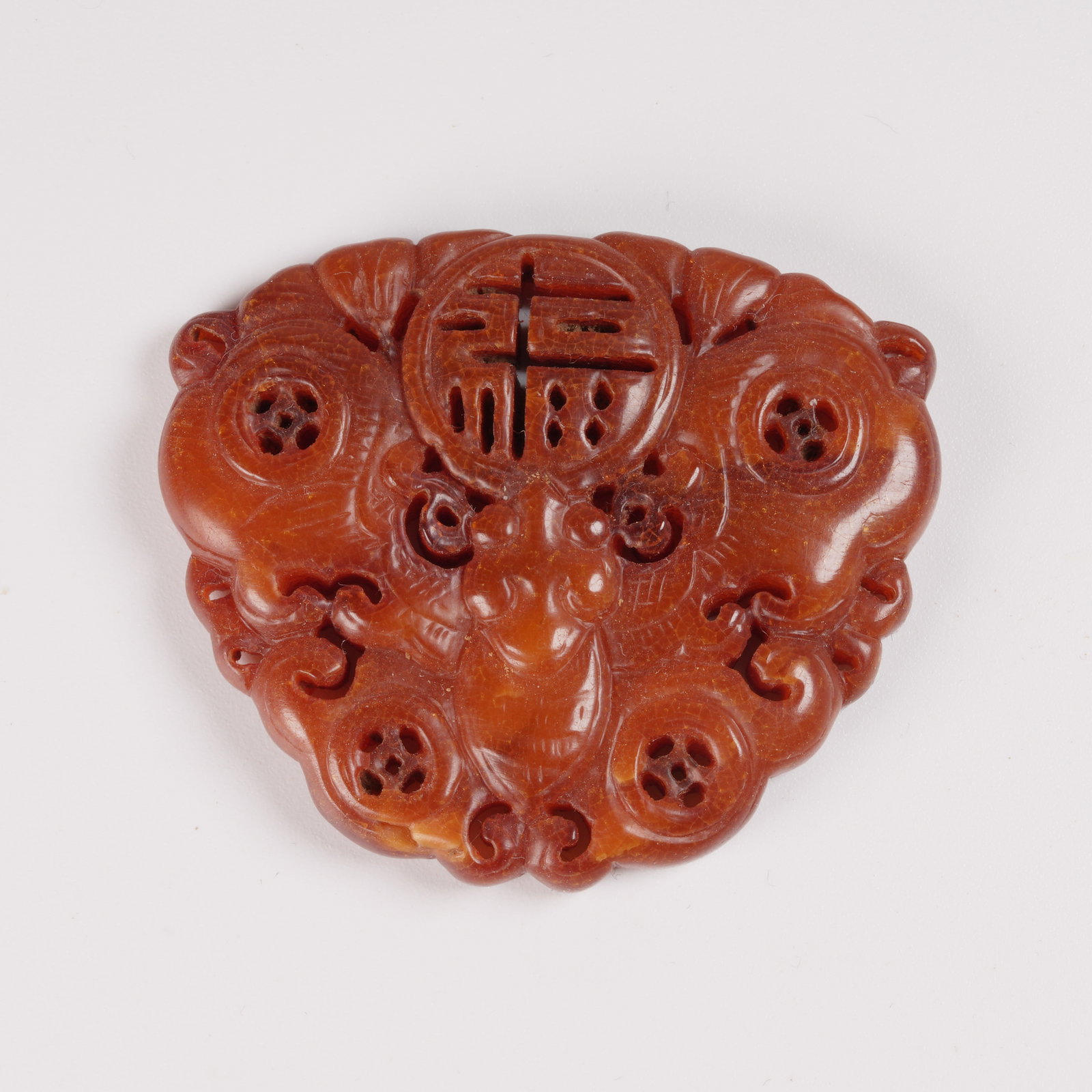 A HONEY-AMBER PENDANT WITH FORTUNE-AND-BUTTERFLY MOTIF: Honey-amber pendant with fortune-and-butterfly motif