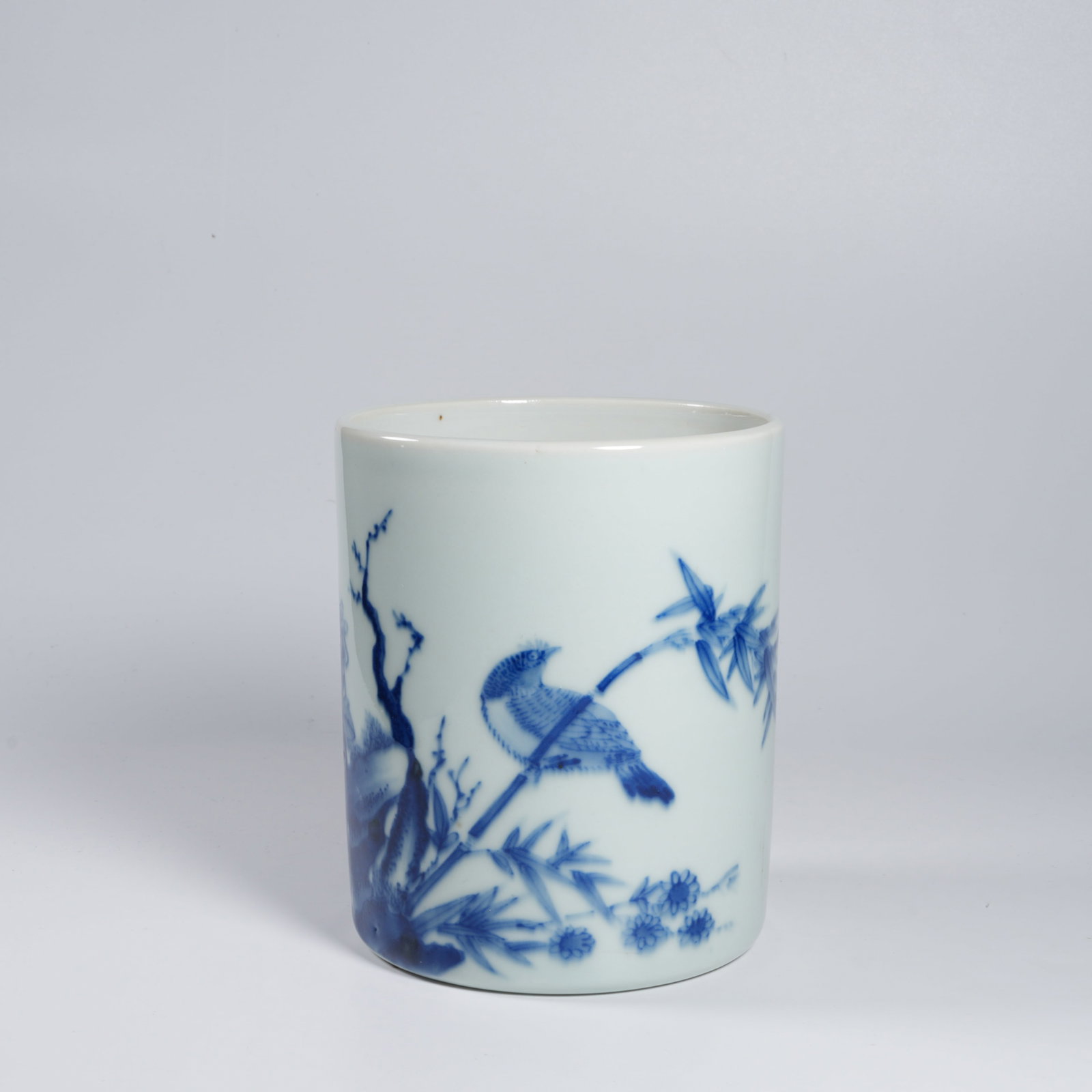 A BLUE-AND-WHITE BIRD-AND-FLOWER BRUSH POT: Blue-and-white bird-and-flower brush pot