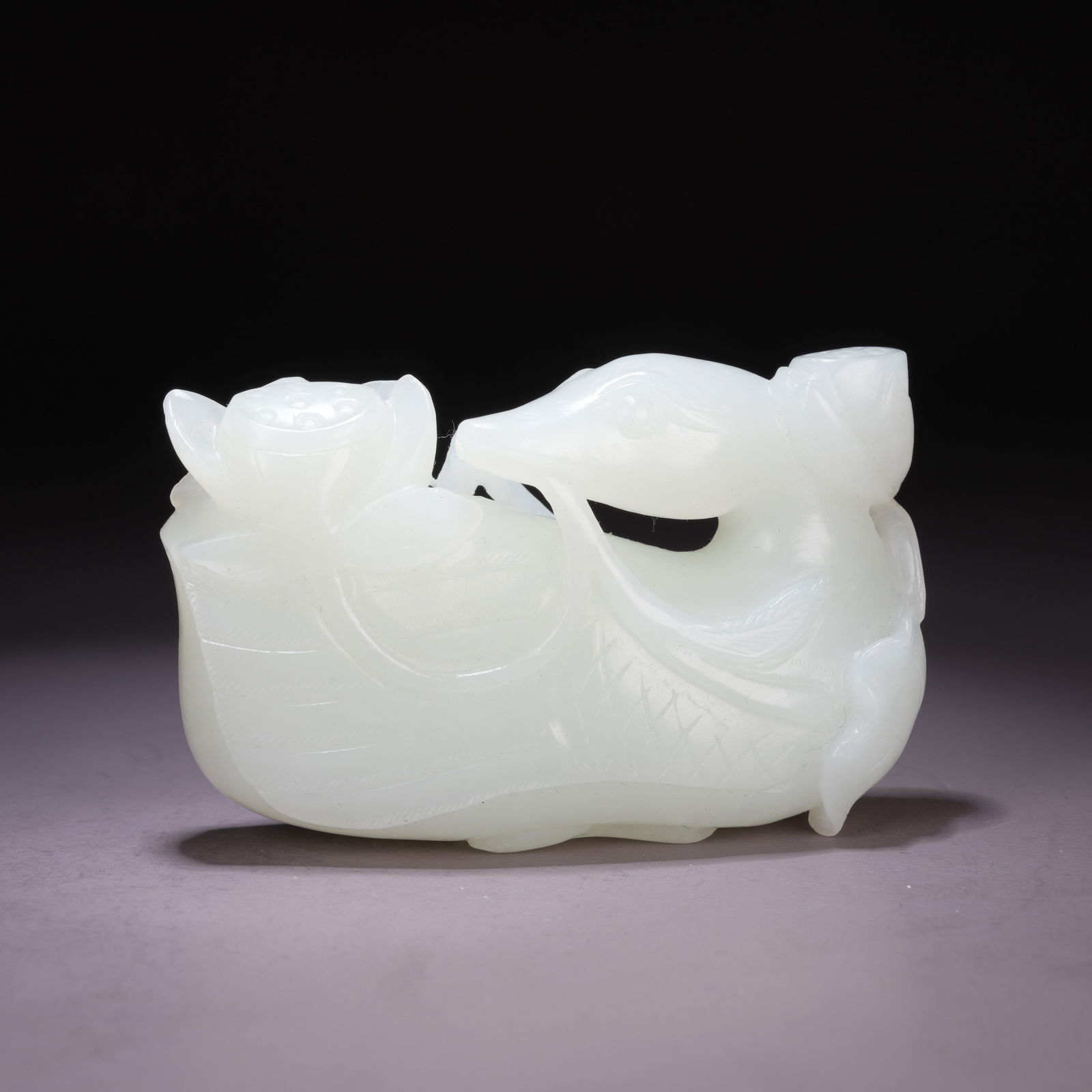 A HETIAN WHITE JADE ORNAMENT OF A TREASURE DUCK HOLDING A LOTUS BLOSSOM: Hetian White Jade Ornament of a Treasure Duck Holding a Lotus Blossom