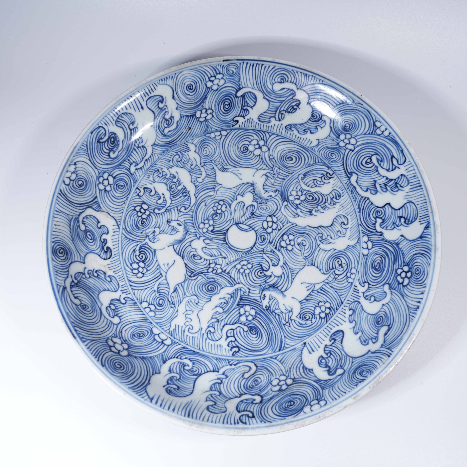 A LARGE BLUE AND WHITE PLATE WITH RESERVED SEAWATER HORSE PATTERN: Large Blue and White Plate with Reserved Seawater Horse Pattern