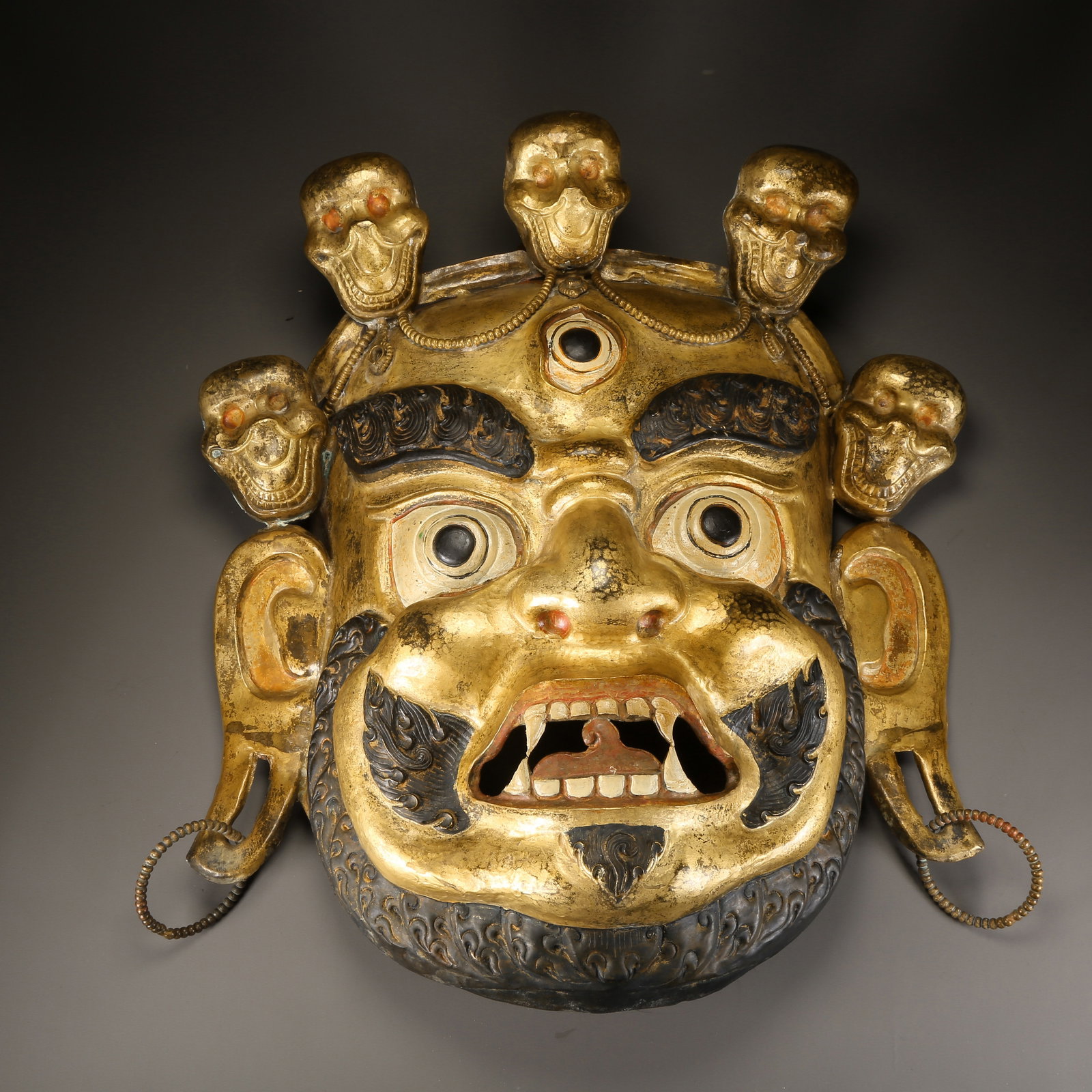 A GILDED BRONZE HAMMERED DHARMAPALA HEAD PENDANT (1 of 8)