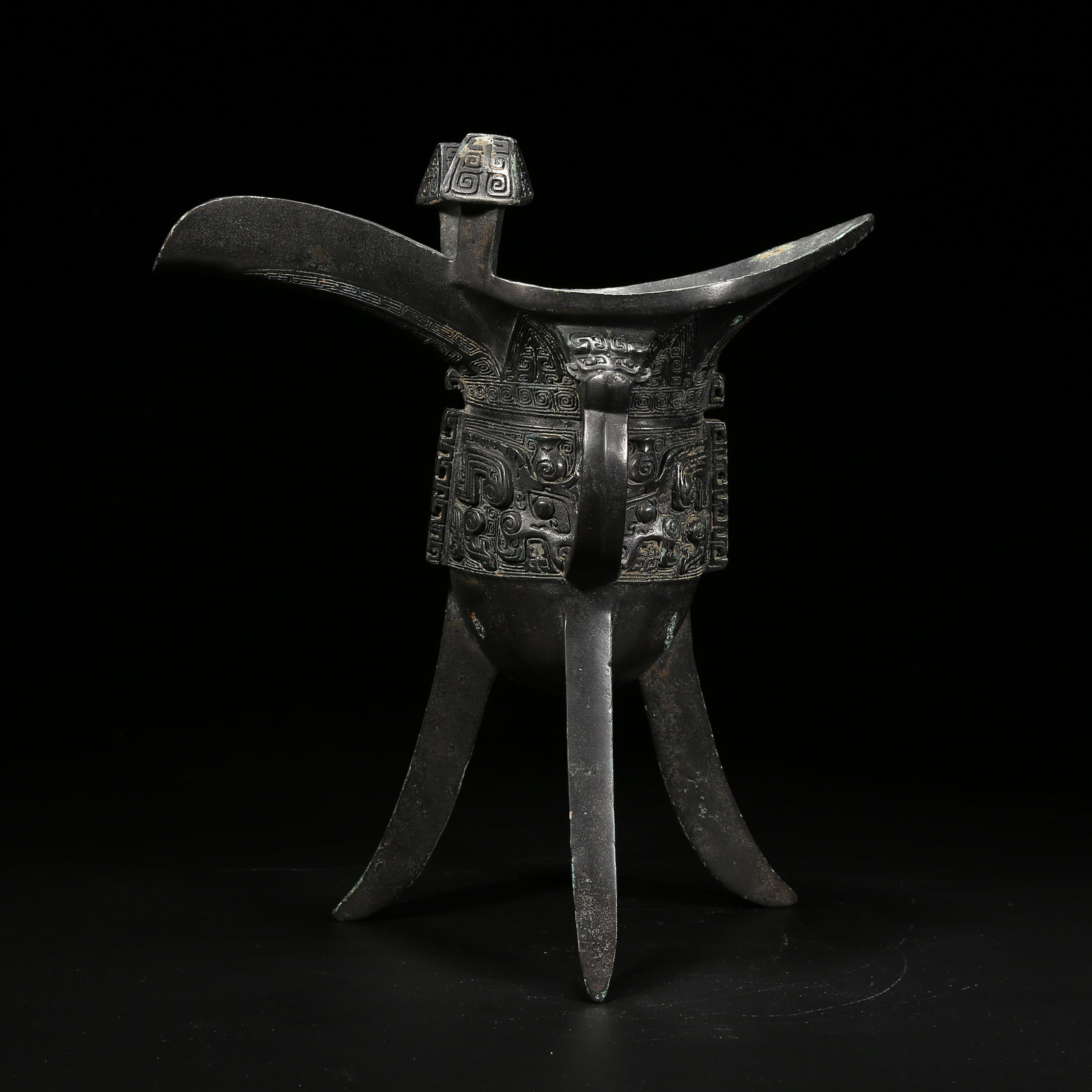 A BRONZE JUE CUP WITH TAOTIE (BEAST FACE) PATTERN: Bronze jue cup with taotie (beast face) pattern