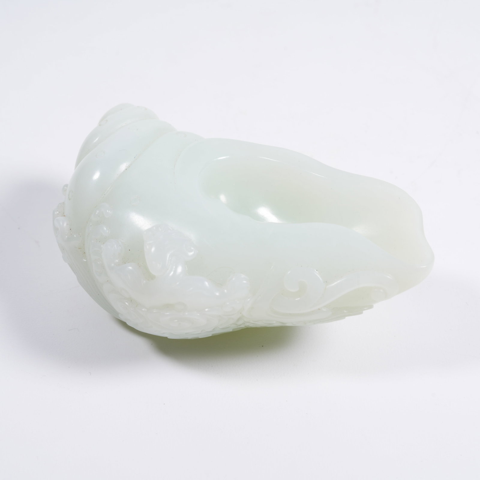 A HETIAN WHITE JADE CONCH-SHAPED INK REST CARVED WITH CHILONG PATTERN: Hetian White Jade Conch-shaped Ink Rest Carved with Chilong Pattern