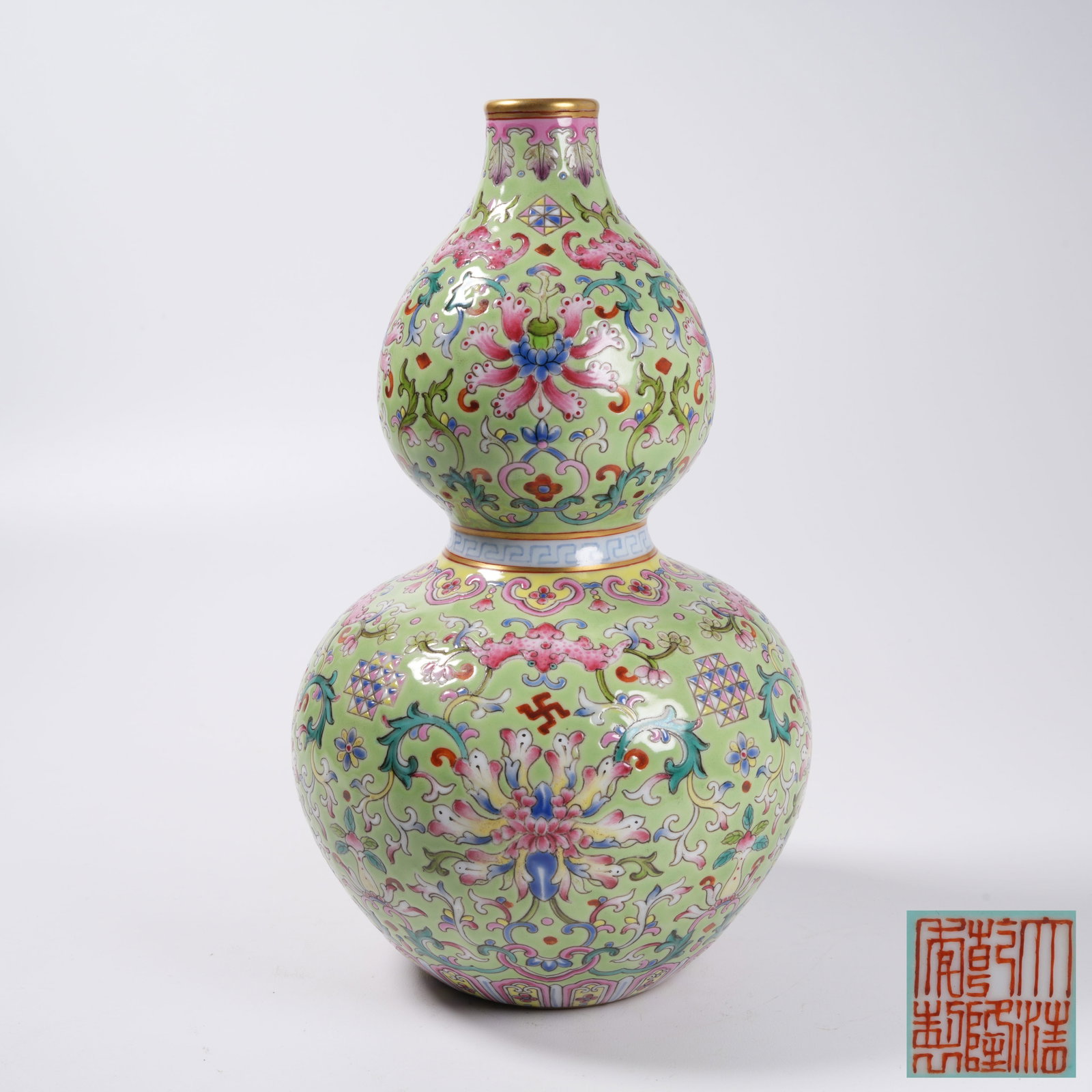 A GREEN GROUND FAMILLE ROSE GOURD VASE WITH INTERLOCKING PRECIOUS FLOWER PATTERN: Green Ground Famille Rose Gourd Vase with Interlocking Precious Flower Pattern
