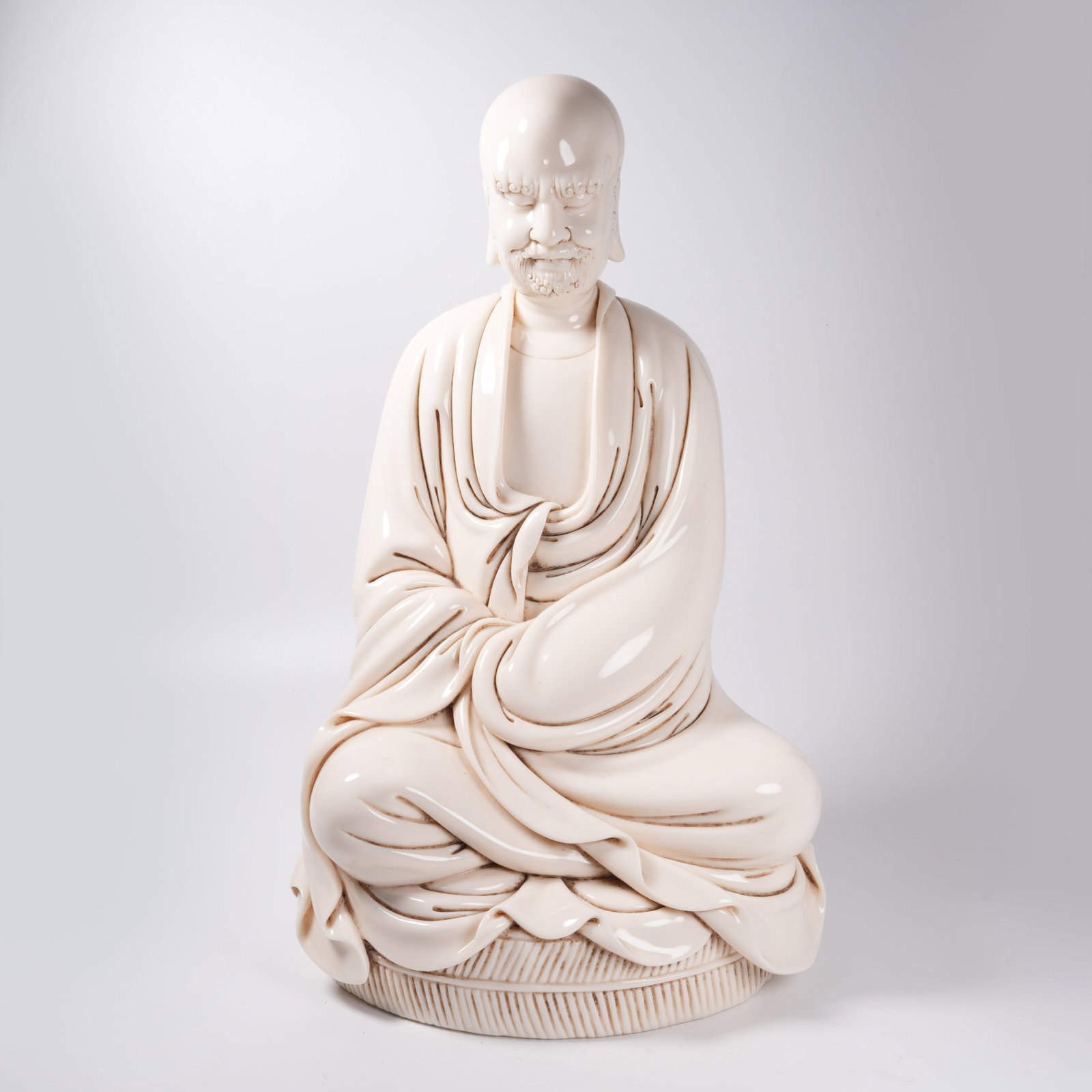 A WHITE PORCELAIN SEATED STATUE OF BODHIDHARMA: White Porcelain Seated Statue of Bodhidharma