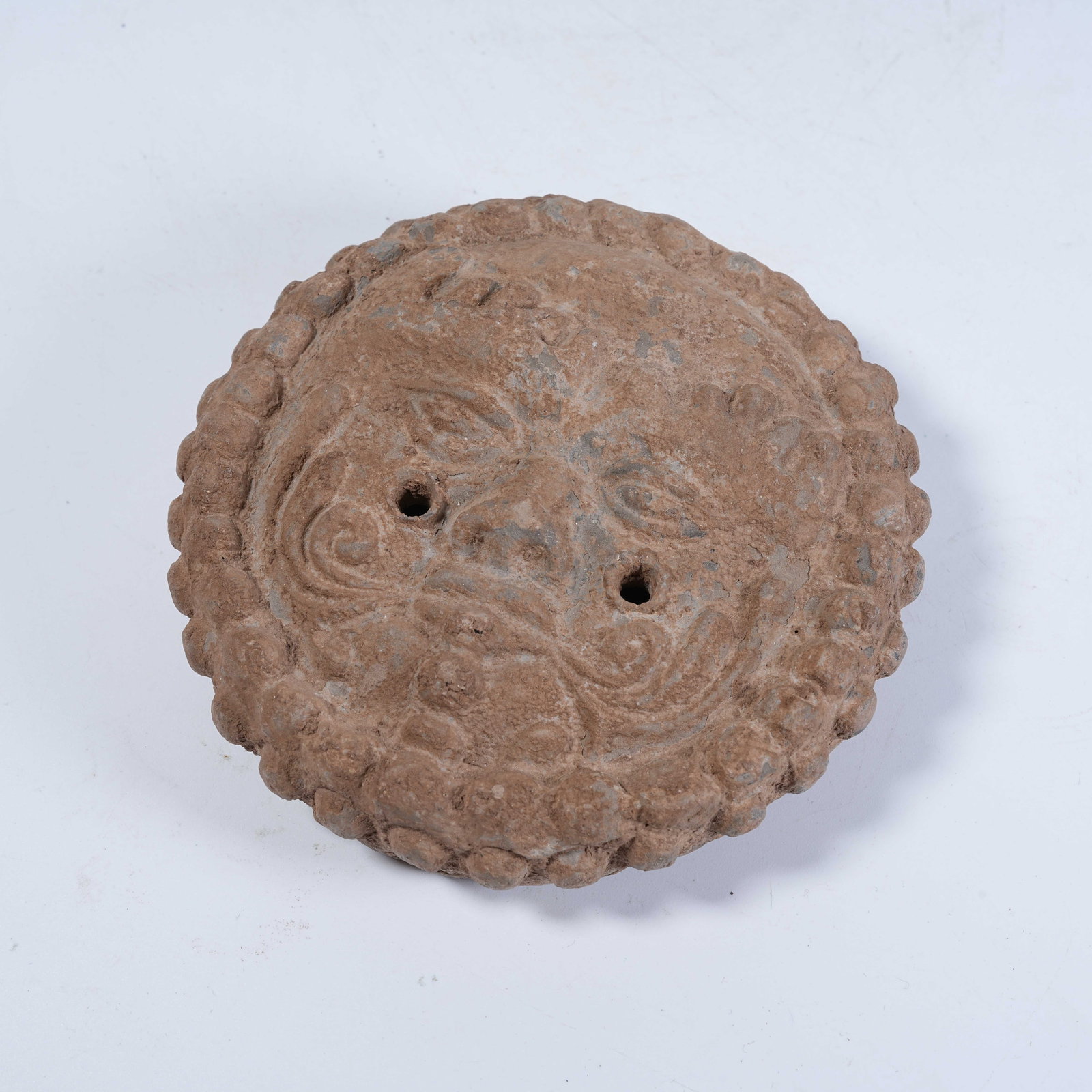 A POTTERY EAVES TILE WITH HUMAN FACE PATTERN: Pottery Eaves Tile with Human Face Pattern
