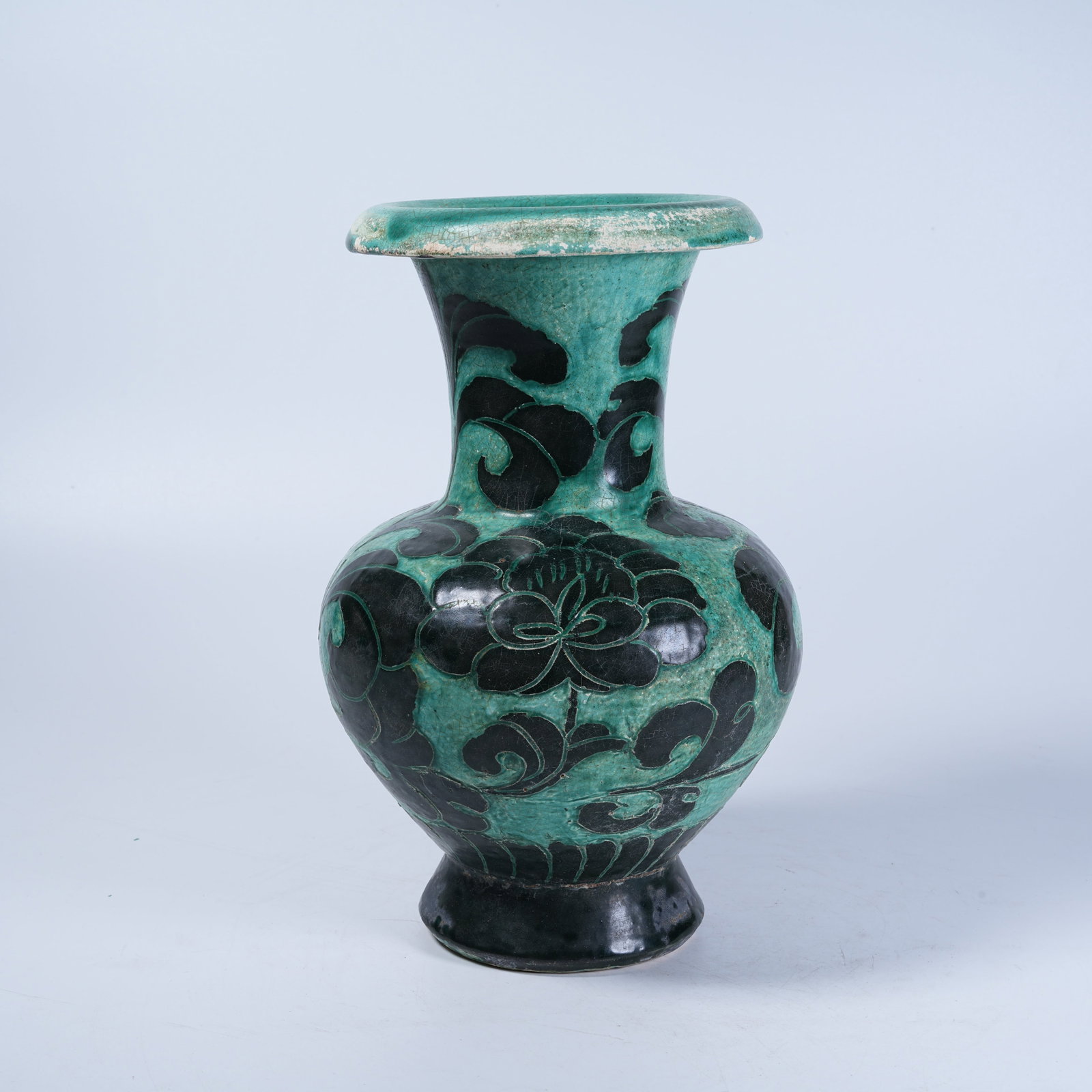 A CIZHOU KILN FLARED-MOUTH VASE WITH SCROLL GRASS PATTERNS CARVED IN BLACK UNDER GREEN GLAZE: Cizhou Kiln Flared-Mouth Vase with Scroll Grass Patterns Carved in Black under Green Glaze