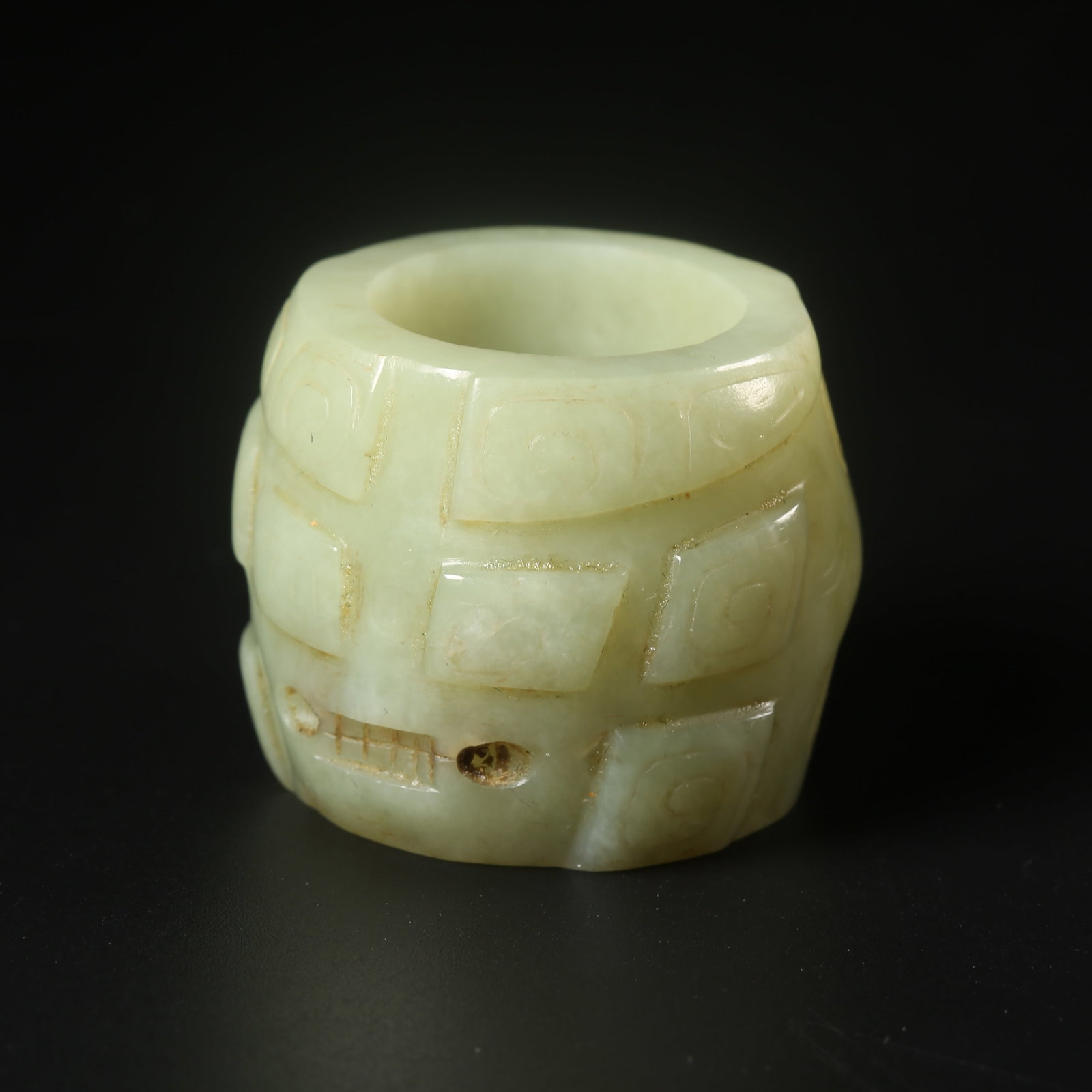 A HETIAN JADE THUMB RING CARVED WITH A DEITY MASK (1 of 9)