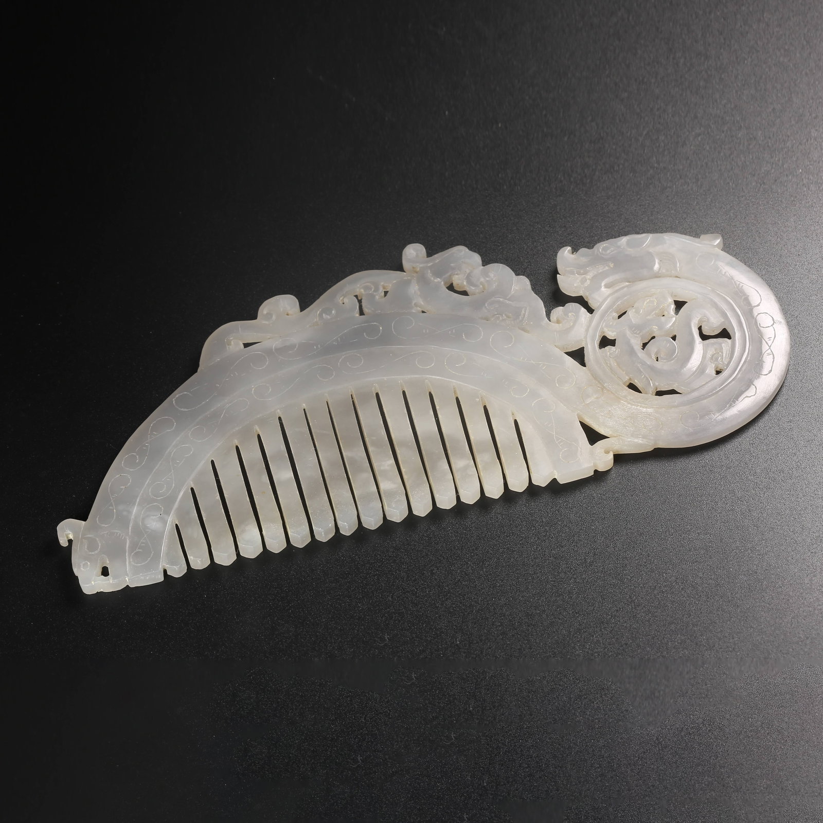 A HETIAN JADE COMB CARVED WITH DRAGON-HEAD FINIAL: Hetian jade comb carved with dragon-head finial