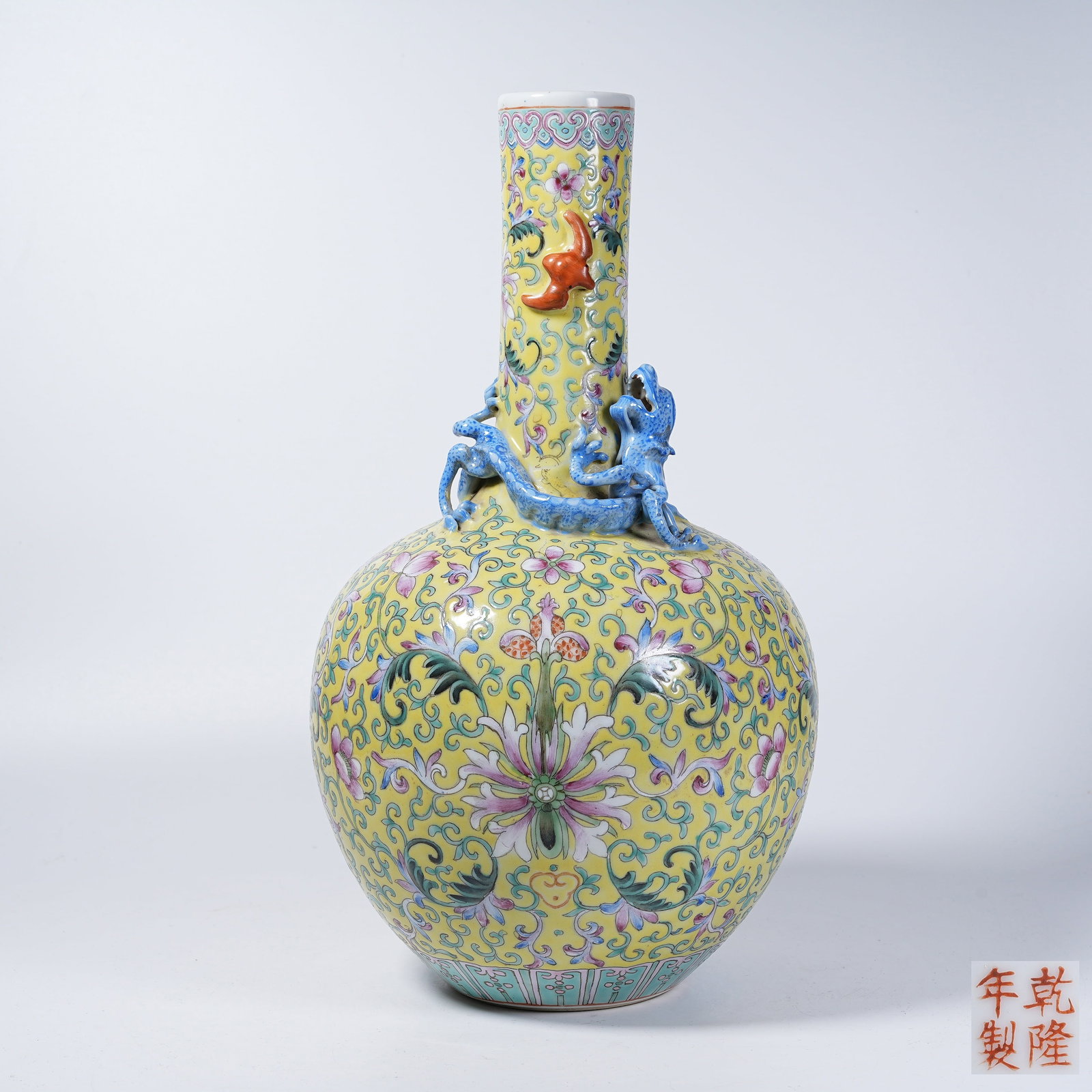 A LONG-NECK VASE WITH YELLOW GROUND FAMILLE ROSE INTERLOCKING FLOWERS HOLDING LONGEVITY CHARACTER: Long-neck Vase with Yellow Ground Famille Rose Interlocking Flowers Holding Longevity Character Pattern