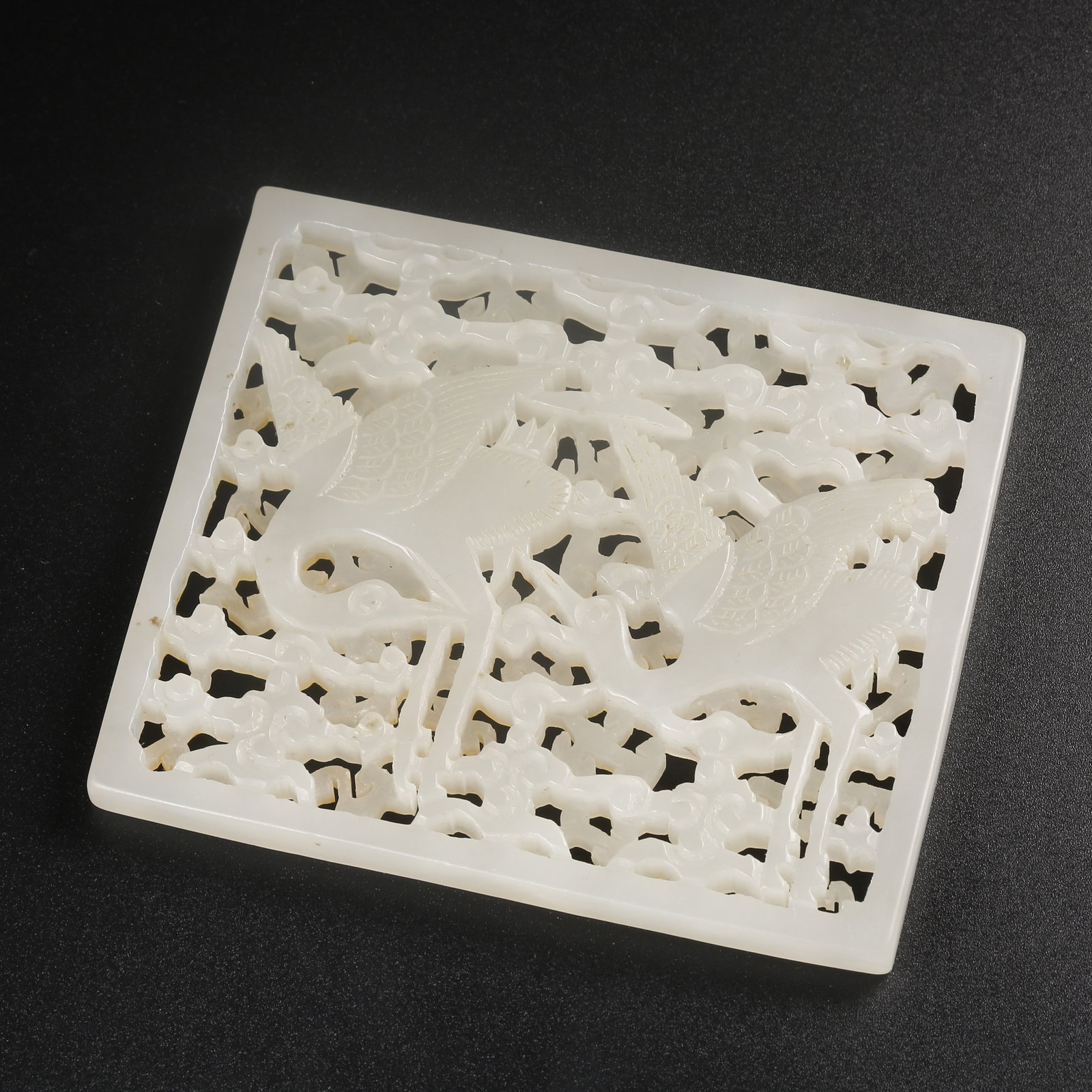 A HETIAN JADE BELT ORNAMENT CARVED WITH CLOUD-AND-PHOENIX MOTIFS: Hetian jade belt ornament carved with cloud-and-phoenix motifs