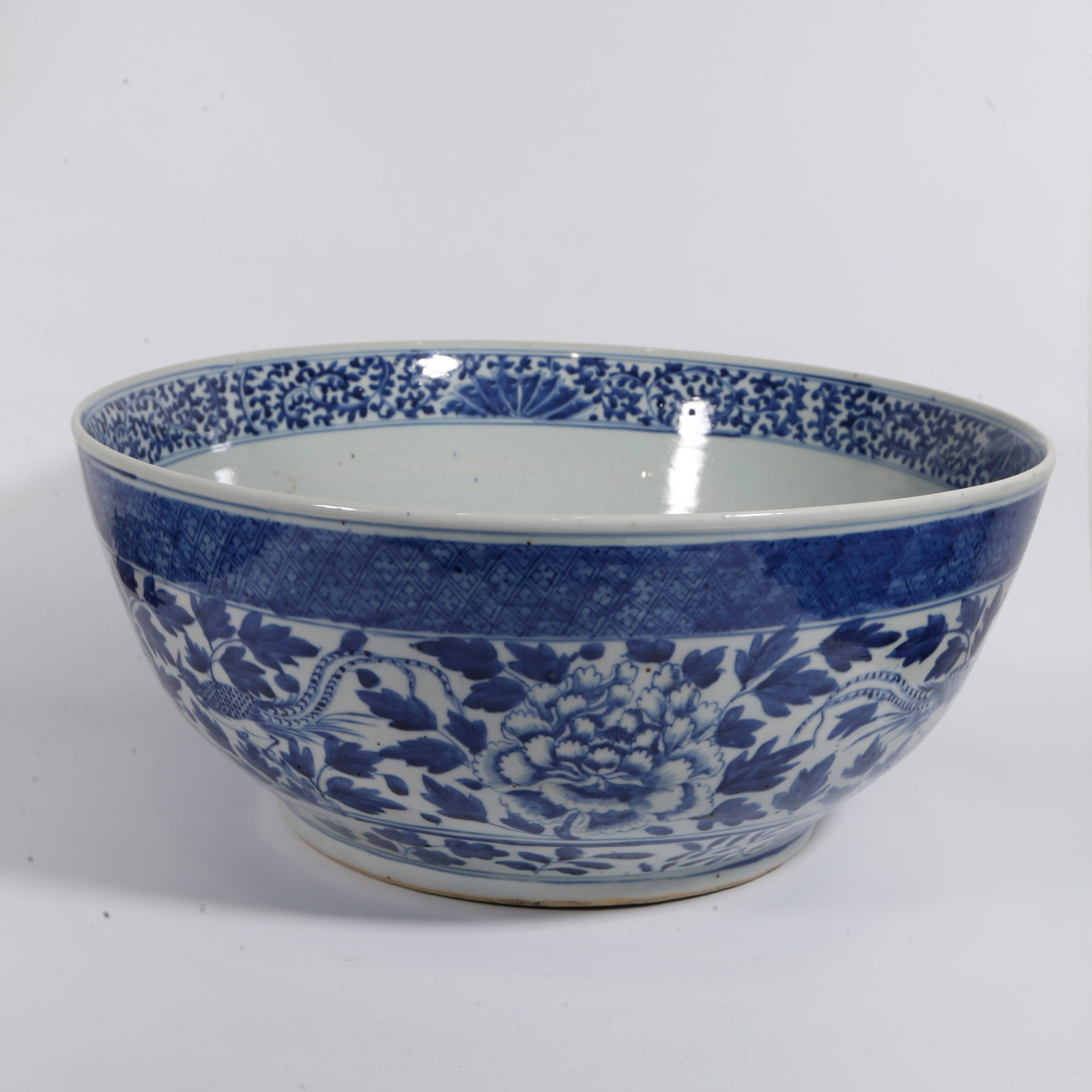 A LARGE BLUE AND WHITE BOWL WITH INTERLOCKING FLORAL SCROLLS: Large Blue and White Bowl with Interlocking Floral Scrolls