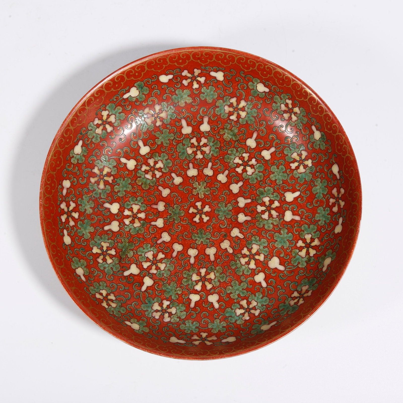 A CORAL RED GROUND FAMILLE ROSE PLATE WITH INTERLOCKING FLORAL SCROLLS: Coral Red Ground Famille Rose Plate with Interlocking Floral Scrolls